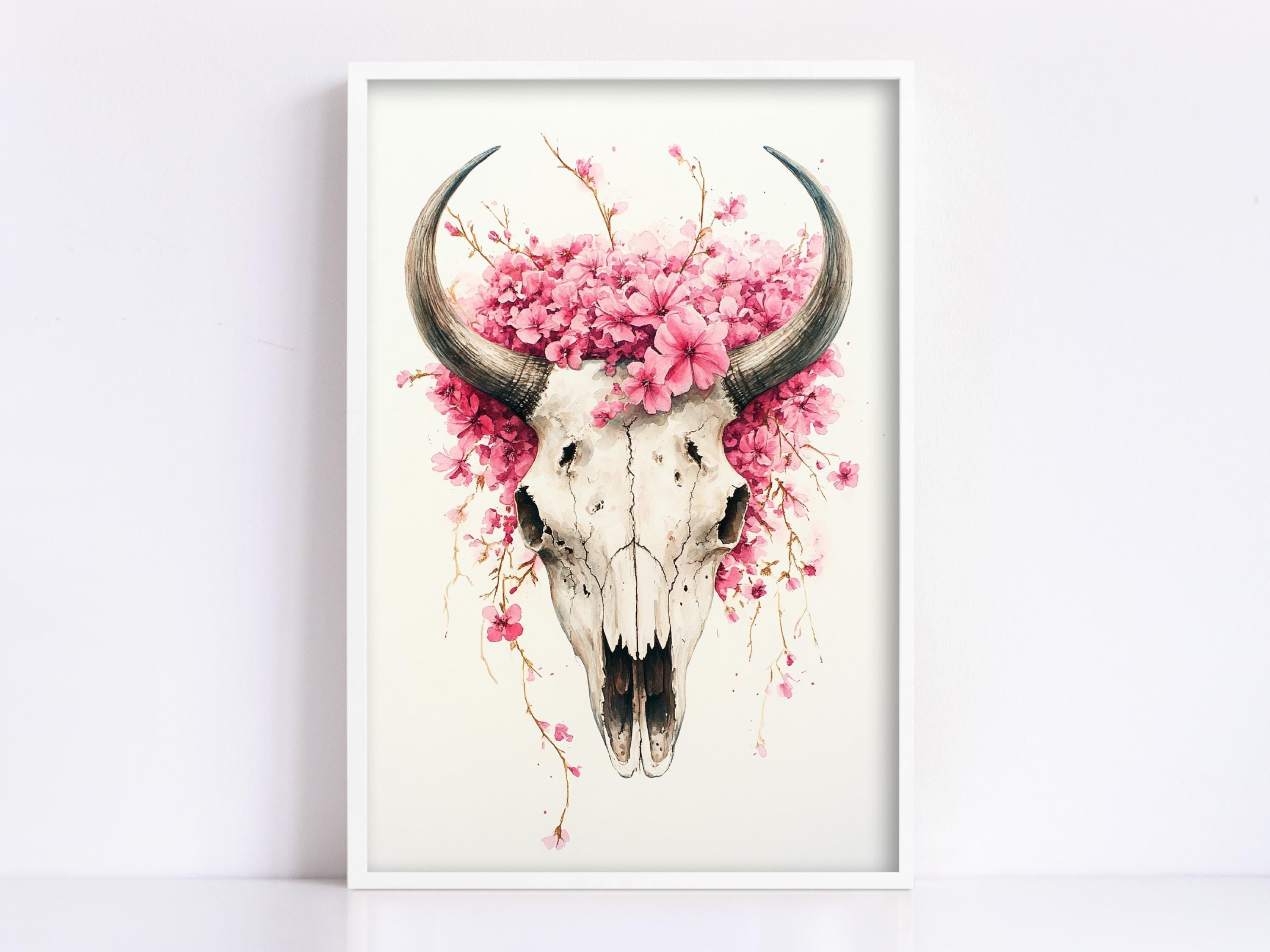 A framed artwork depicting a skull with large horns and a floral arrangement on top.