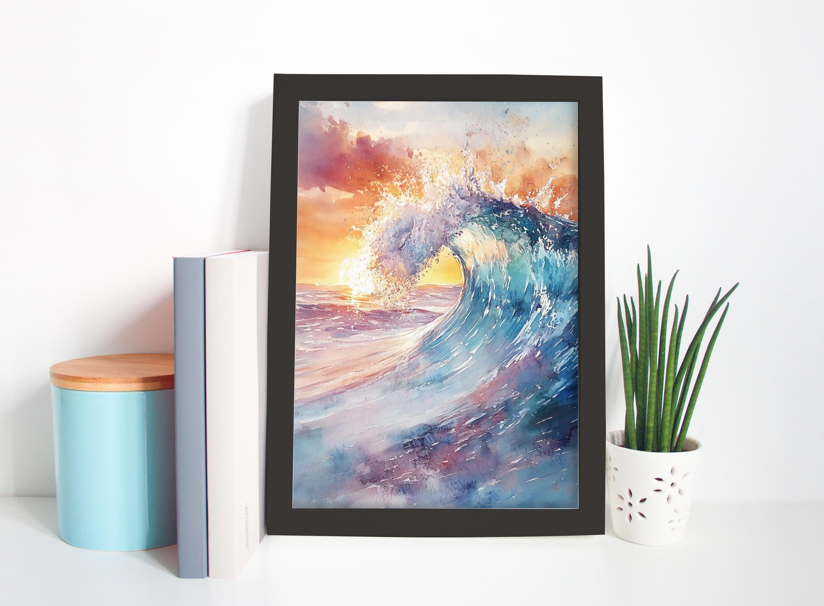 a framed painting of a crashing wave, with a vibrant sunset in the background. The painting is displayed on a white wall, and there are a few decorative items placed around it, including a blue container, a white vase, and a plant.