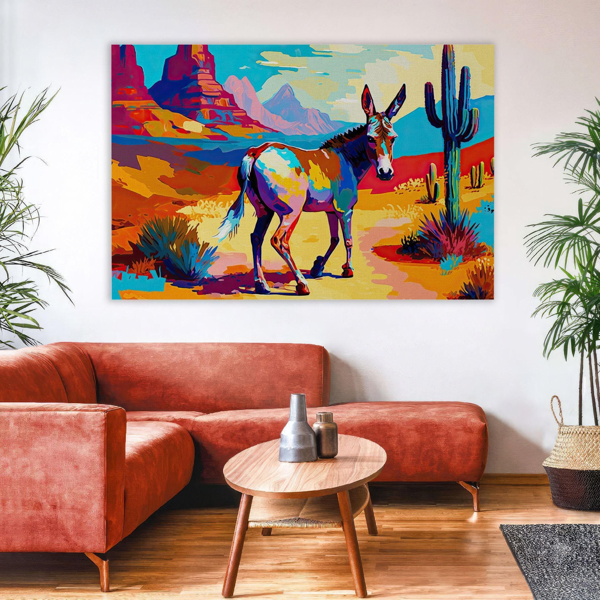 a vibrant painting of a donkey in a desert landscape, hanging on a wall above a red sofa and a wooden coffee table.