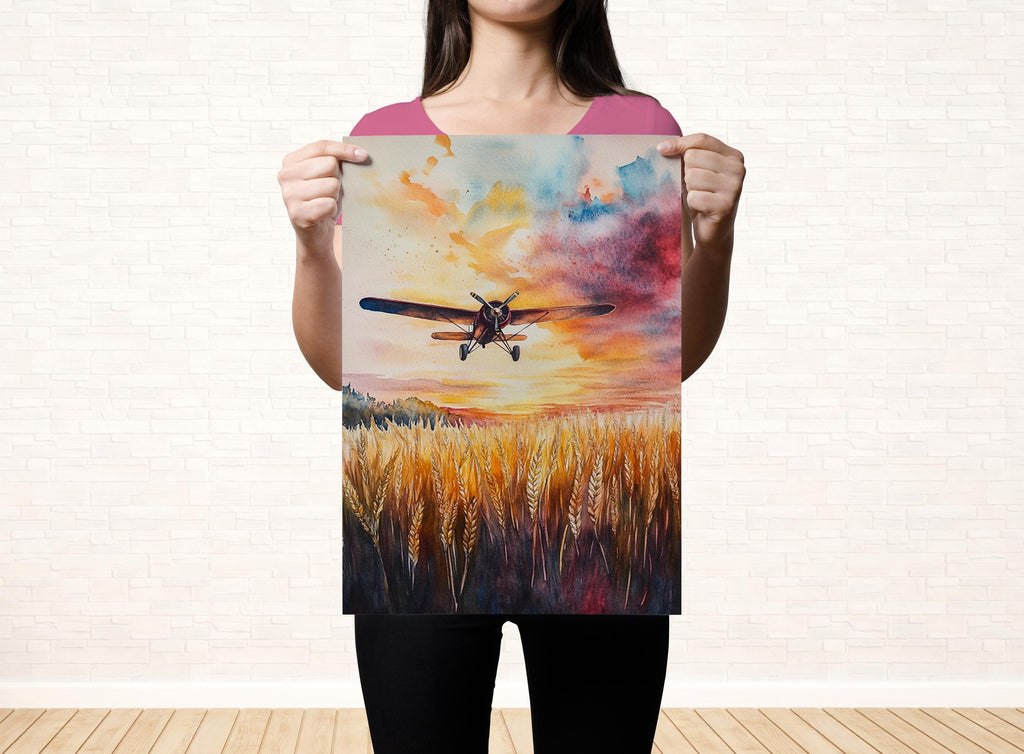 A woman holds up a framed painting depicting a colorful sunset over a field of tall grass.