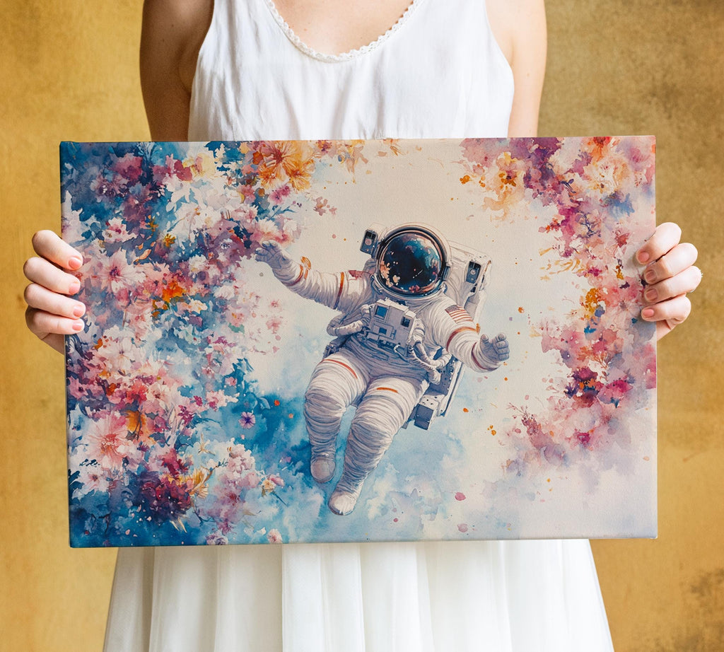 A person is holding a canvas print featuring an astronaut floating in a colorful, floral-themed space.