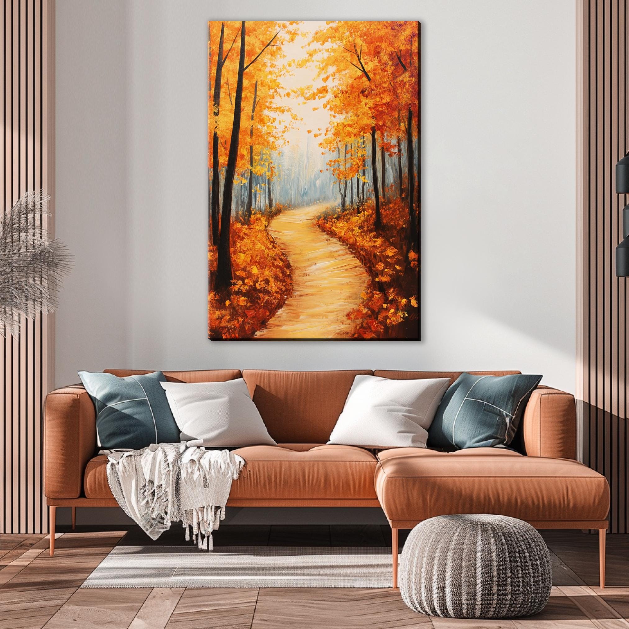 a cozy living room with a large painting of a forest path in autumn hanging on the wall above a brown leather sofa.