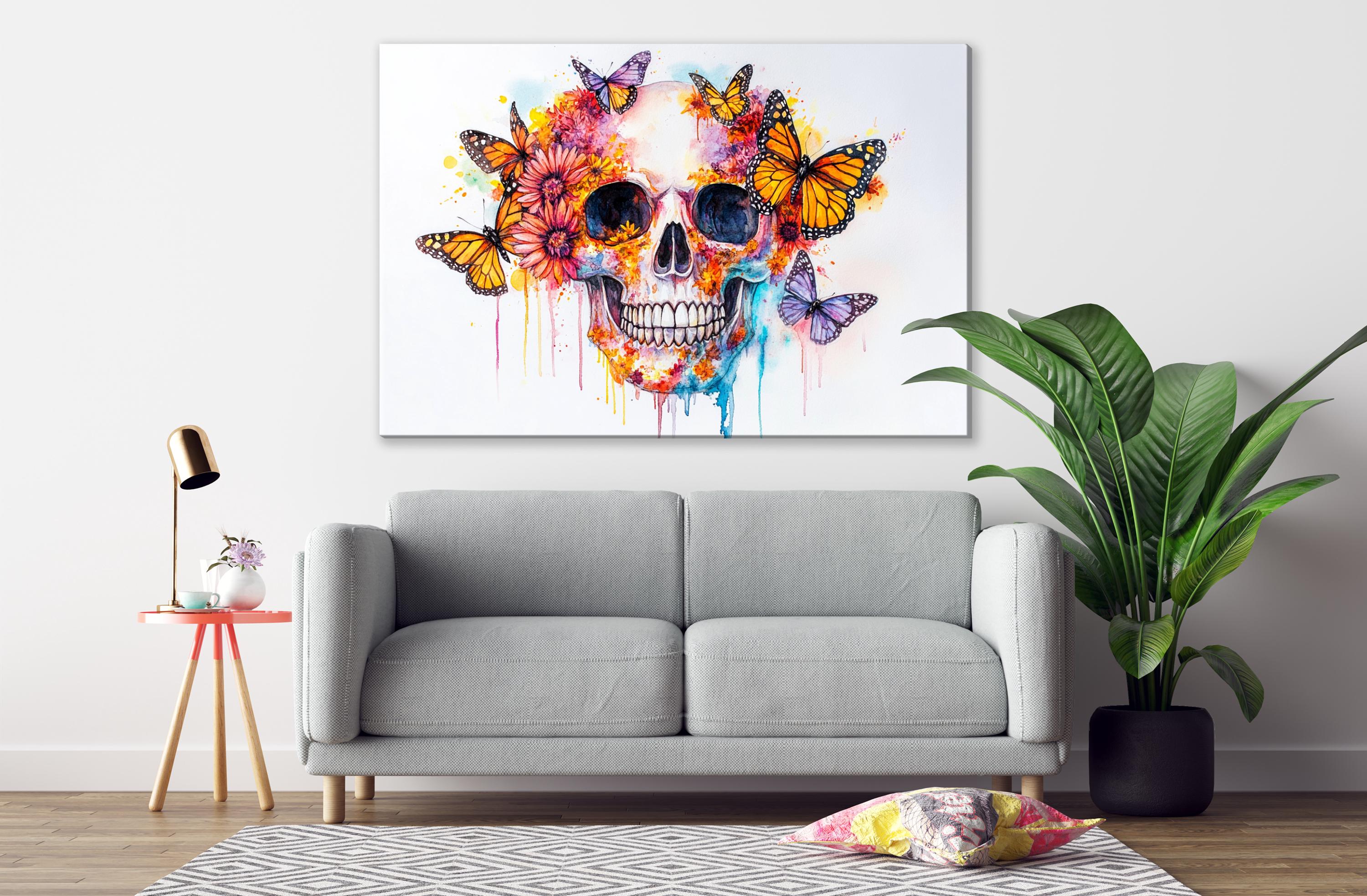 a large, colorful painting of a skull with butterflies adorning its head, hanging on a wall above a gray sofa in a living room setting.