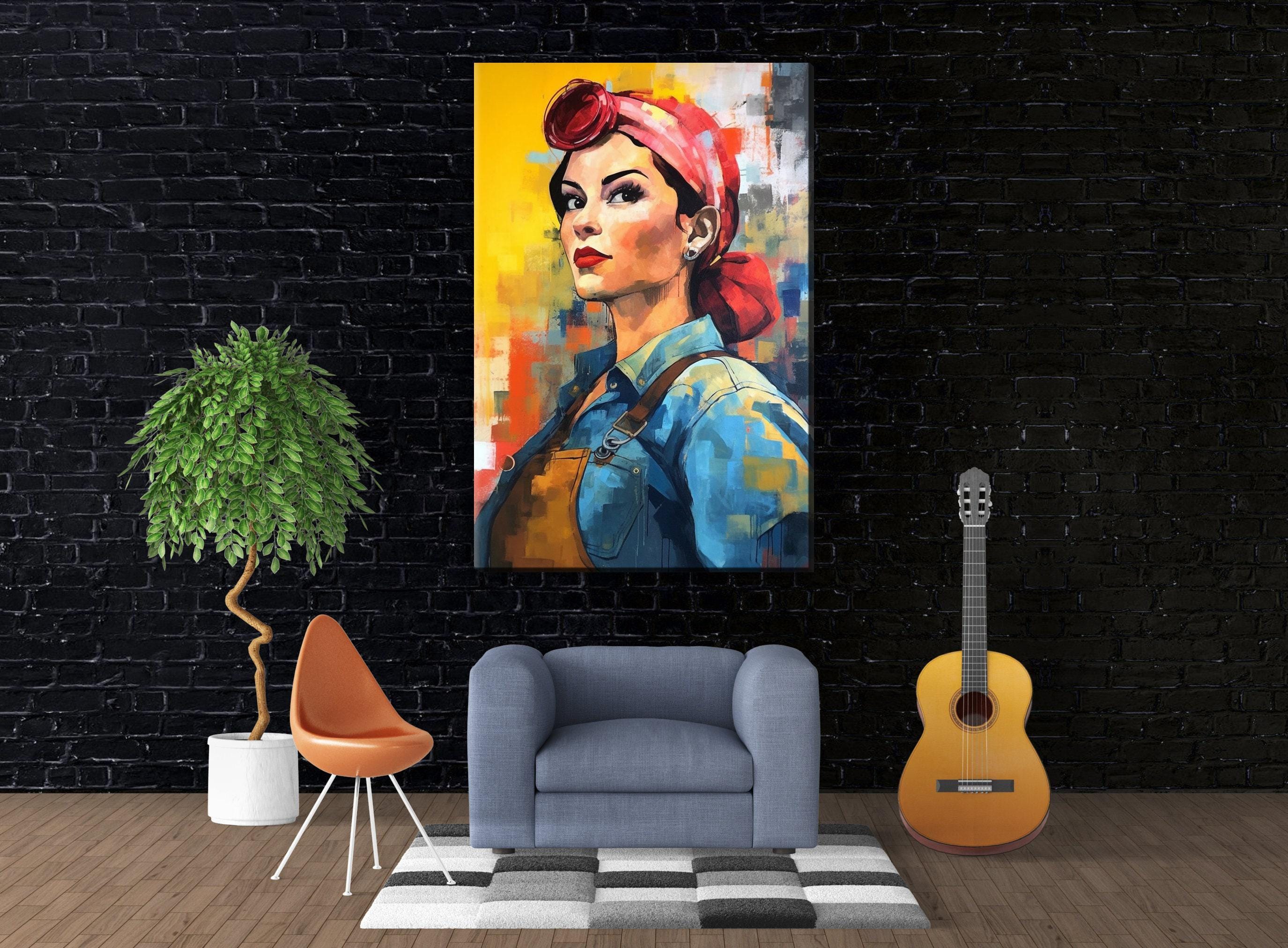 a large, colorful painting of a woman with a red headband, hanging on a black brick wall. In front of the painting, there is a gray armchair, a potted plant, and a guitar.