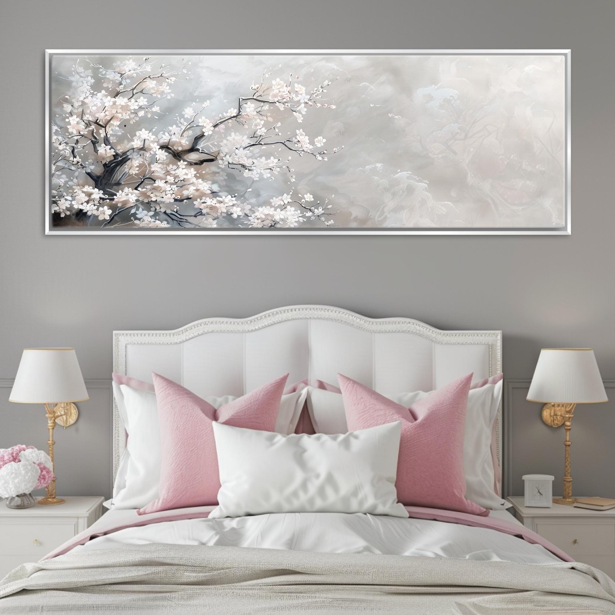 a white bed with pink pillows and a painting on the wall