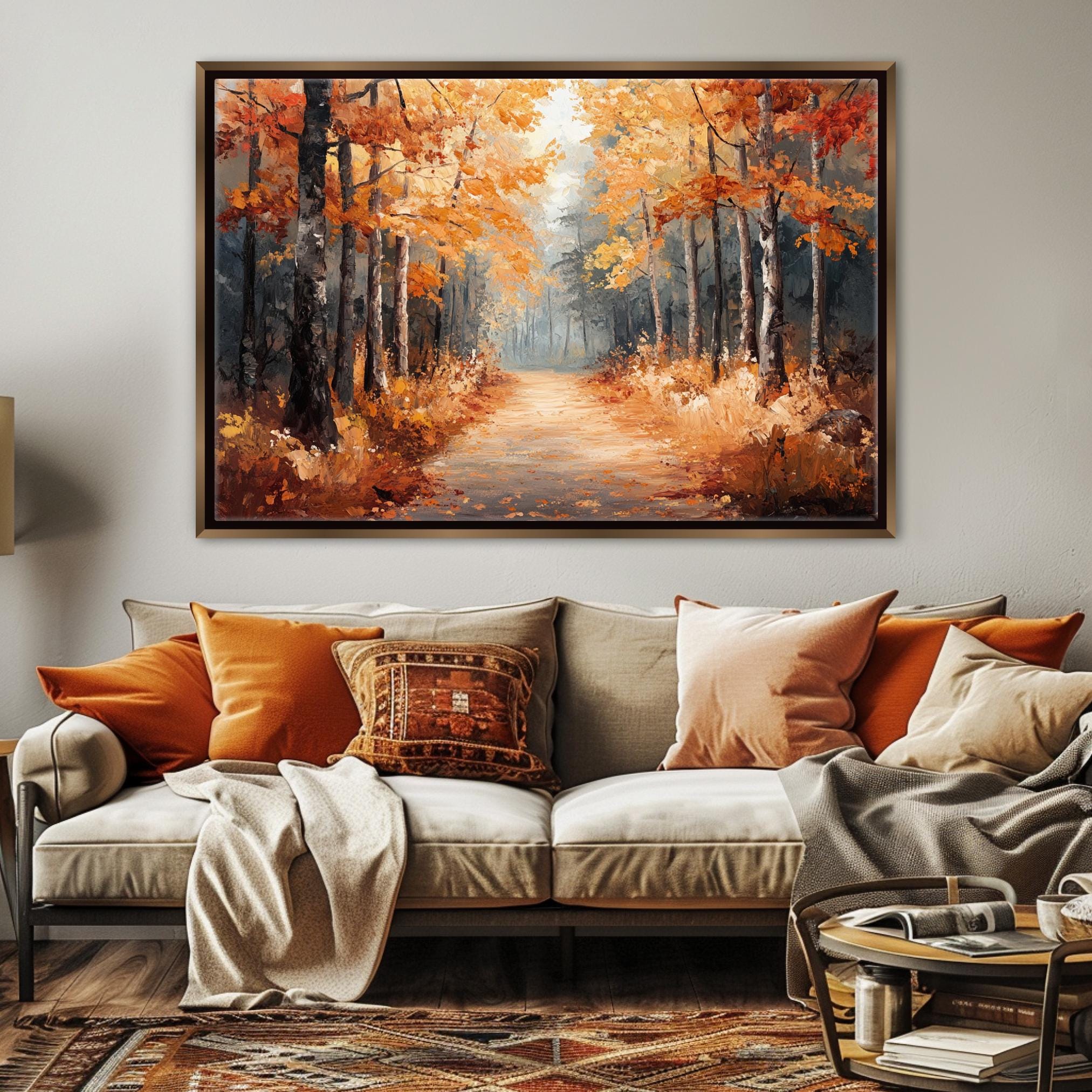 a large painting of a forest path with autumn trees hanging over the top of a couch in a living room setting.