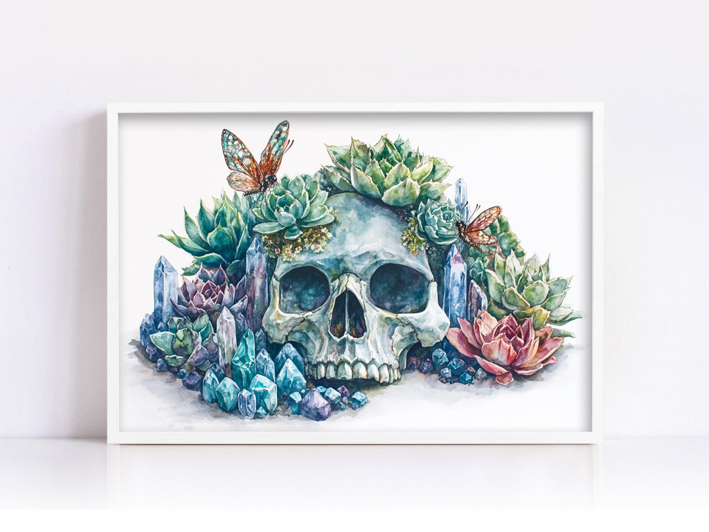 A framed watercolor painting depicting a skull surrounded by a variety of colorful plants, including succulents, flowers, and butterflies.
