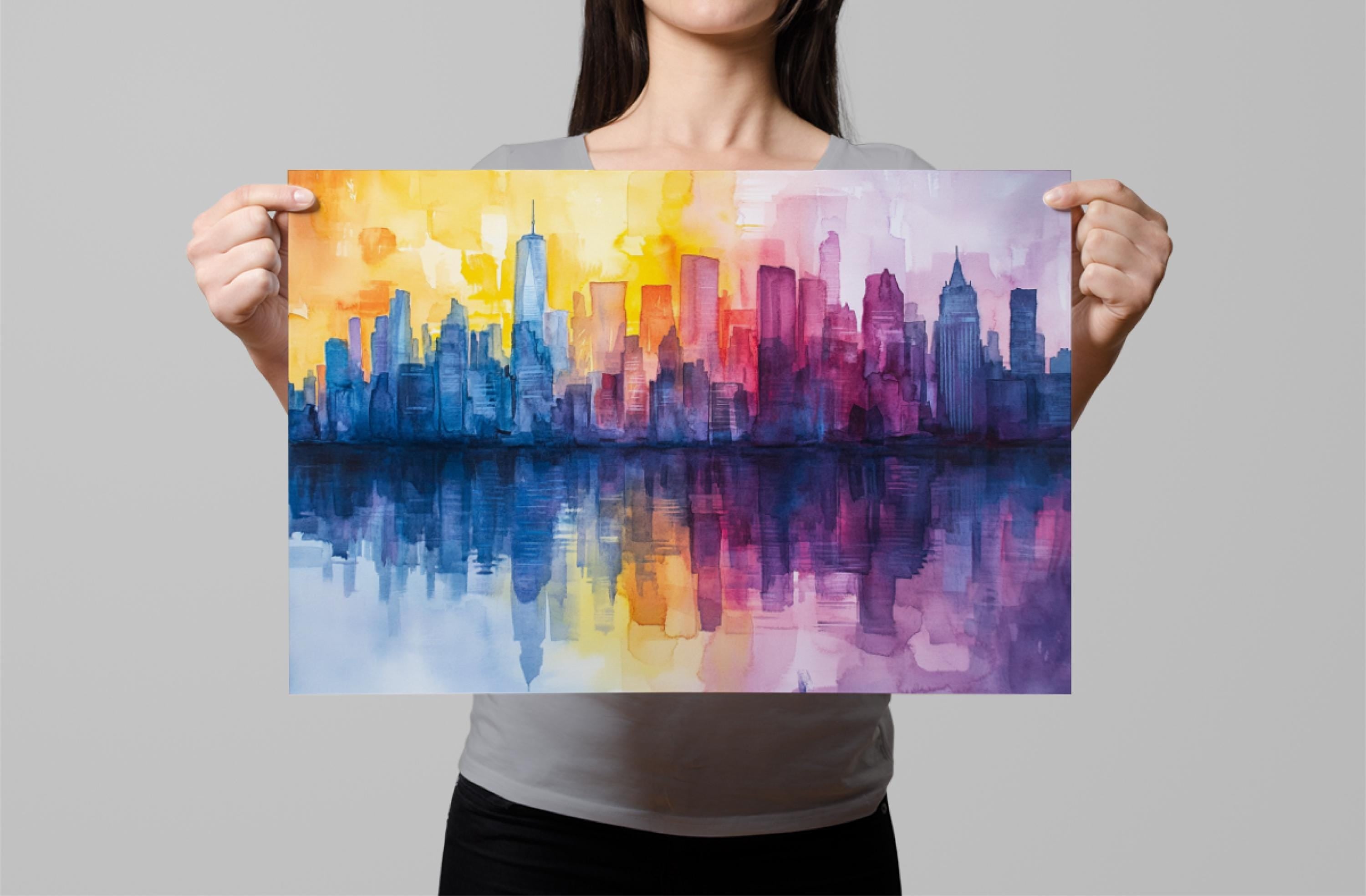 A woman holds up a vibrant watercolor painting depicting a city skyline with a reflection in the water below.