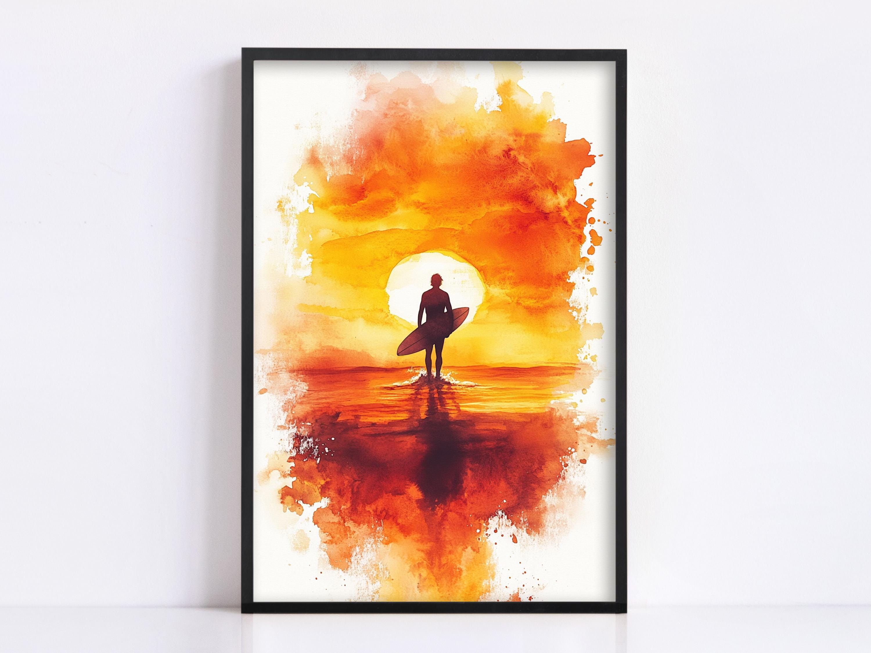 A framed watercolor painting depicting a surfer silhouetted against a vibrant sunset over the ocean.