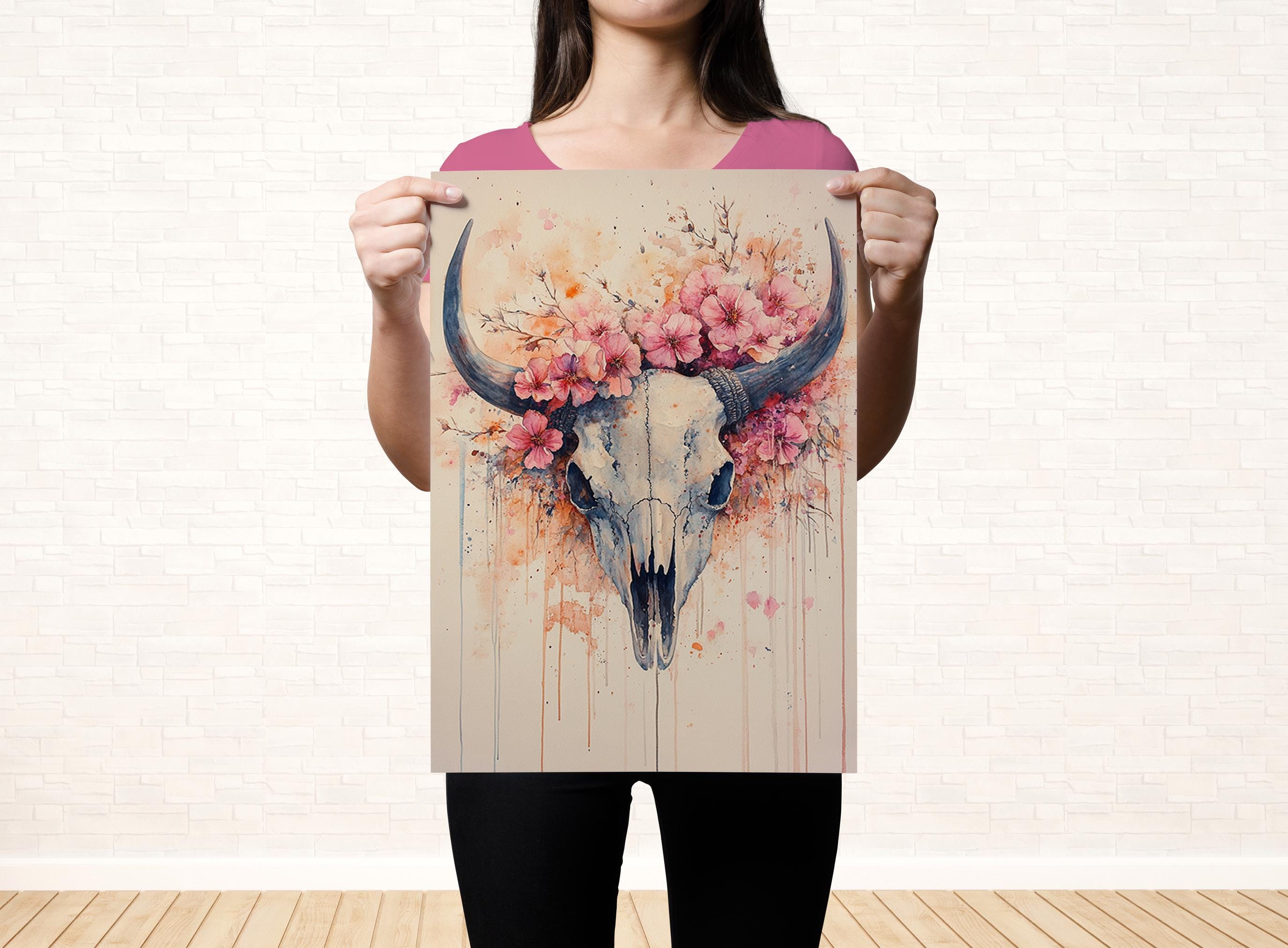 A woman holds up a poster featuring a stylized skull with a floral design.