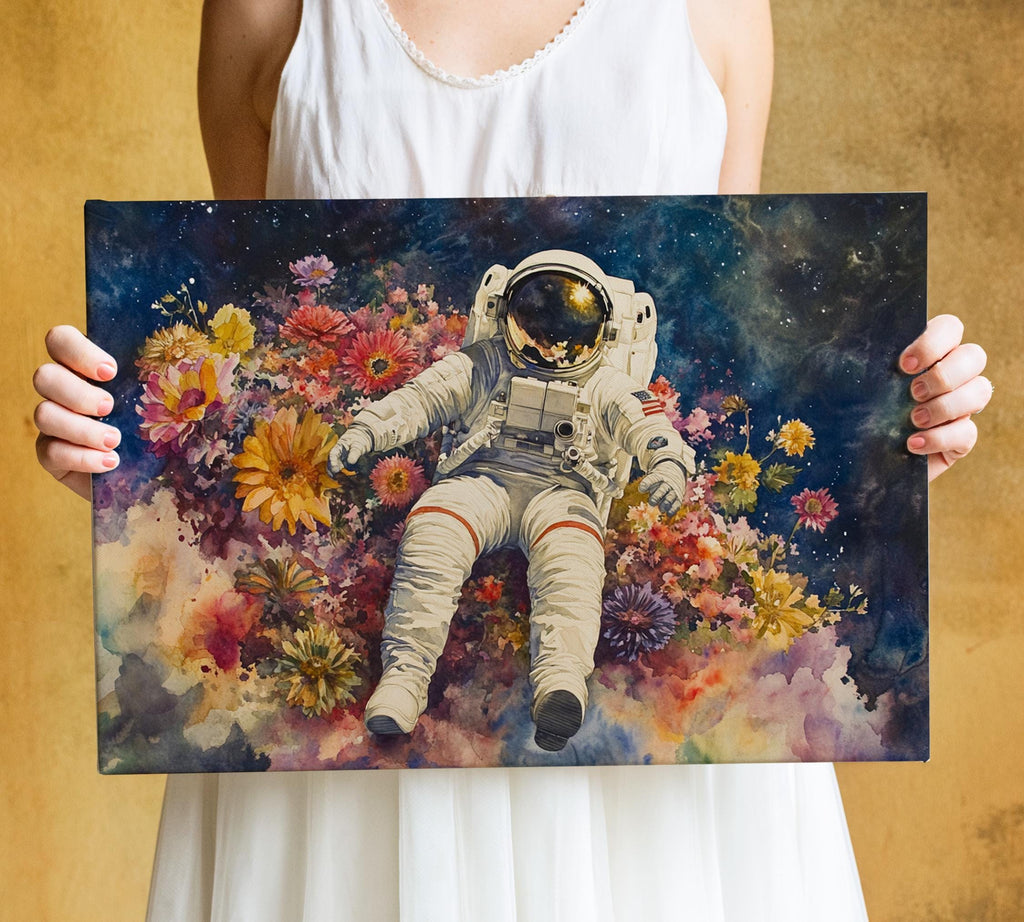 A person is holding a framed print featuring an astronaut floating in a colorful, flower-filled space.