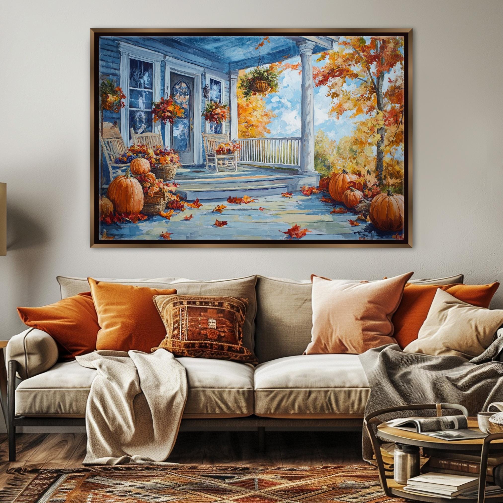 a cozy living room with a large painting of a porch adorned with pumpkins and autumn leaves hanging on the wall above a beige sofa with orange and beige throw pillows.