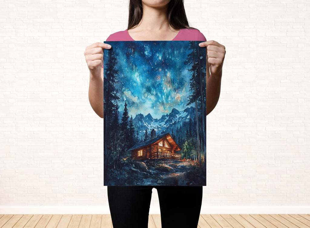 A woman holds up a framed painting depicting a cabin in a forest setting, with a starry night sky in the background.