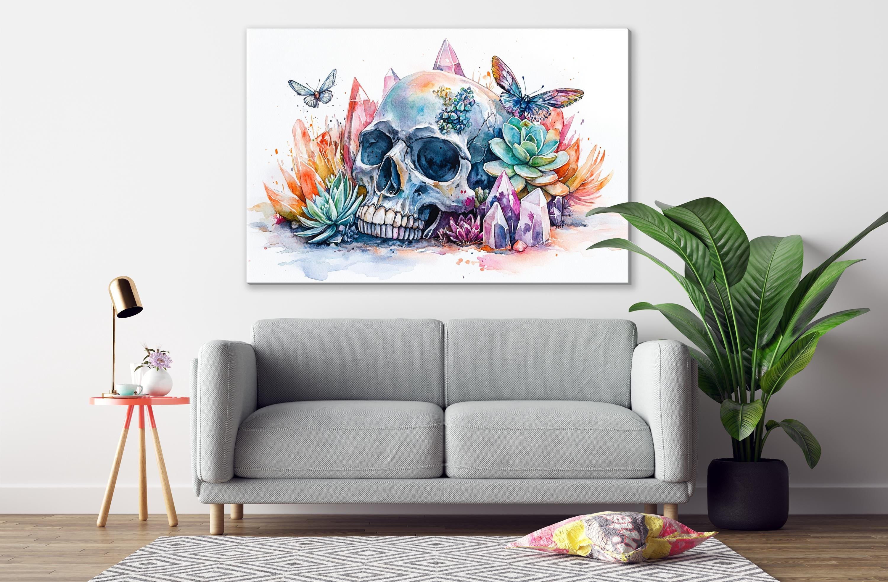 a gray sofa, a pink stool, a large potted plant, and a colorful painting of a skull surrounded by flowers and butterflies on the wall above the sofa.