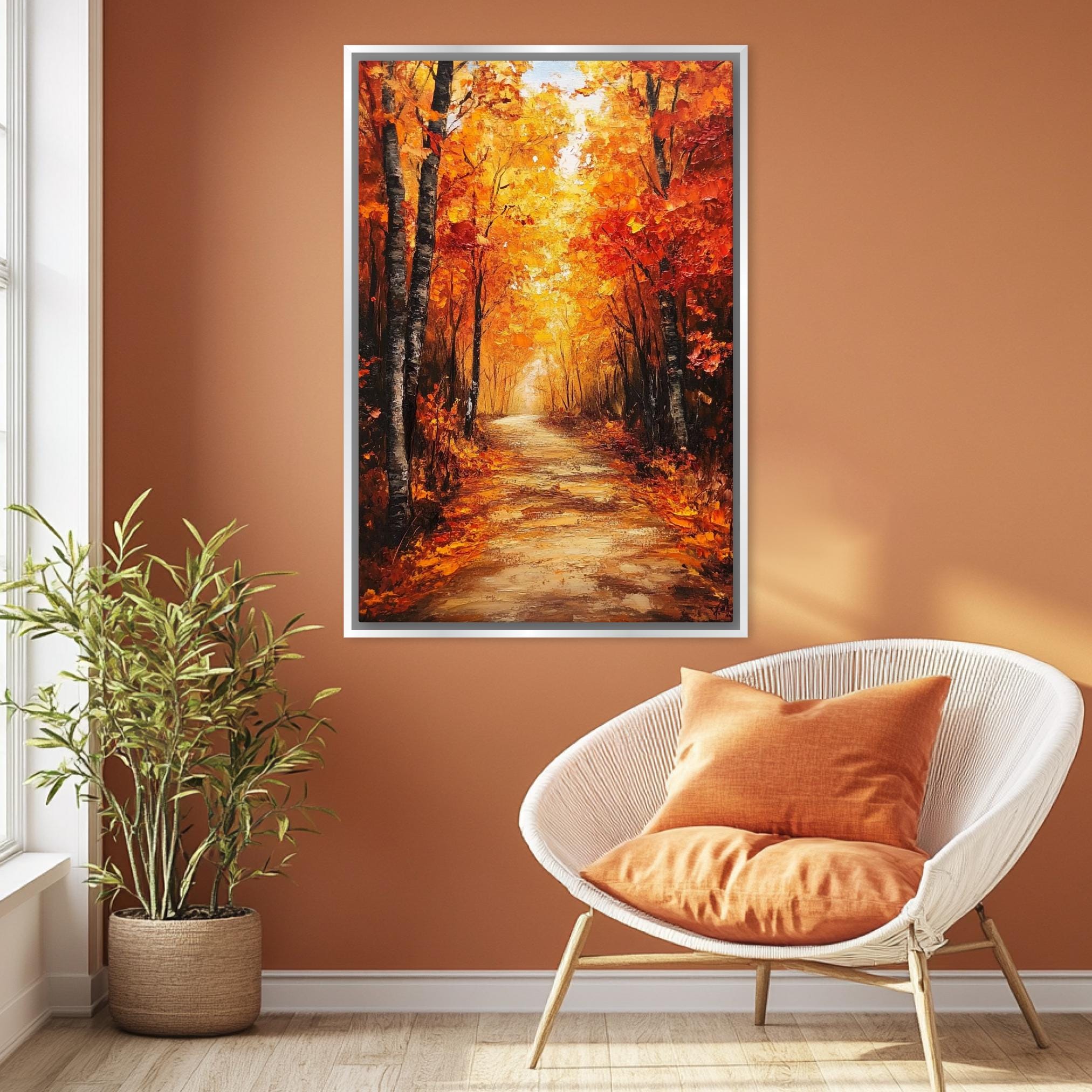 a cozy living room with a large painting of a forest path in autumn hanging on the wall. The painting is framed and appears to be a vibrant representation of a scenic forest trail. The room is furnished with a white wicker chair and a potted plant, creating a warm and inviting atmosphere.