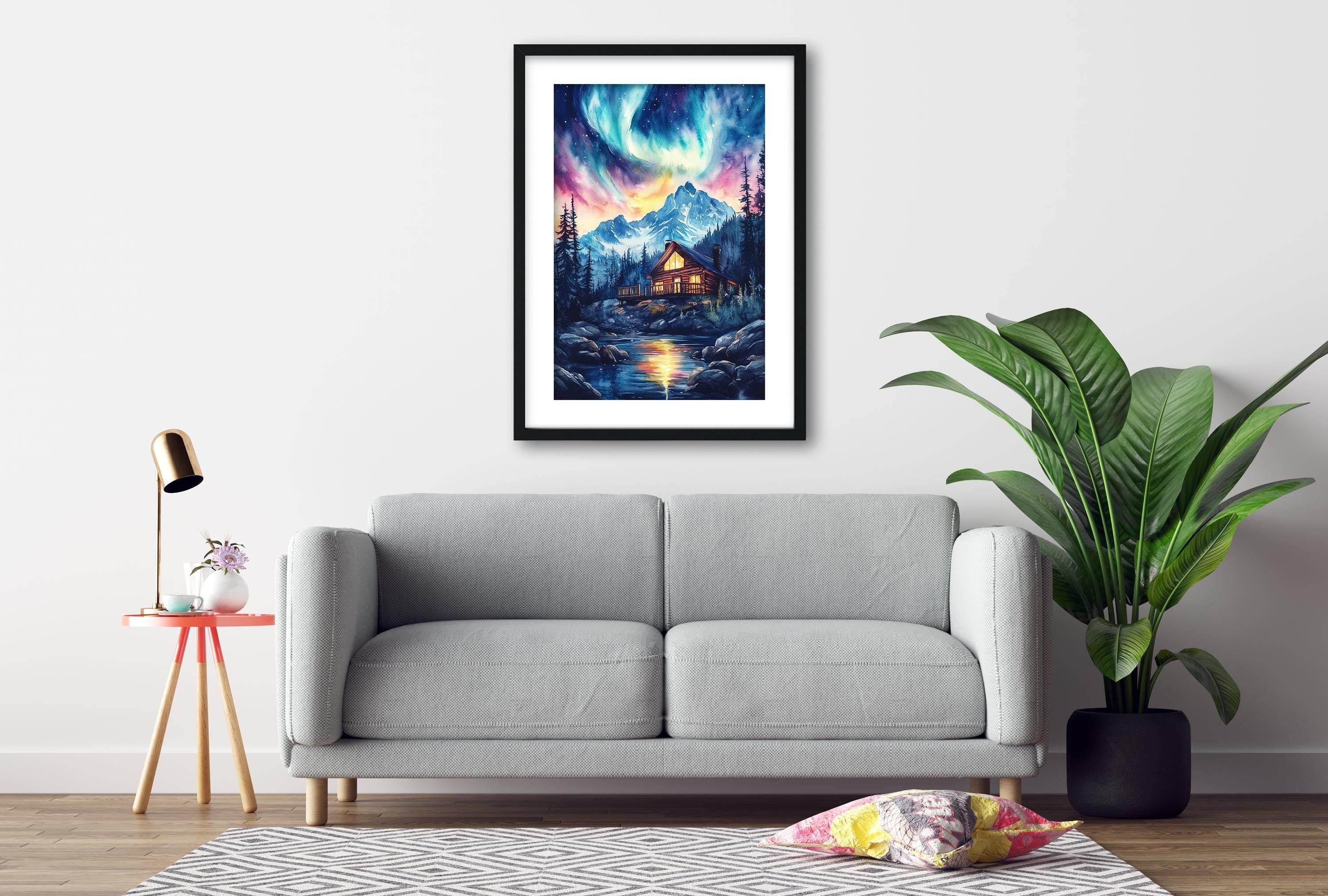 a cozy living room with a gray sofa, a framed painting of a mountain landscape with a cabin, and a potted plant.