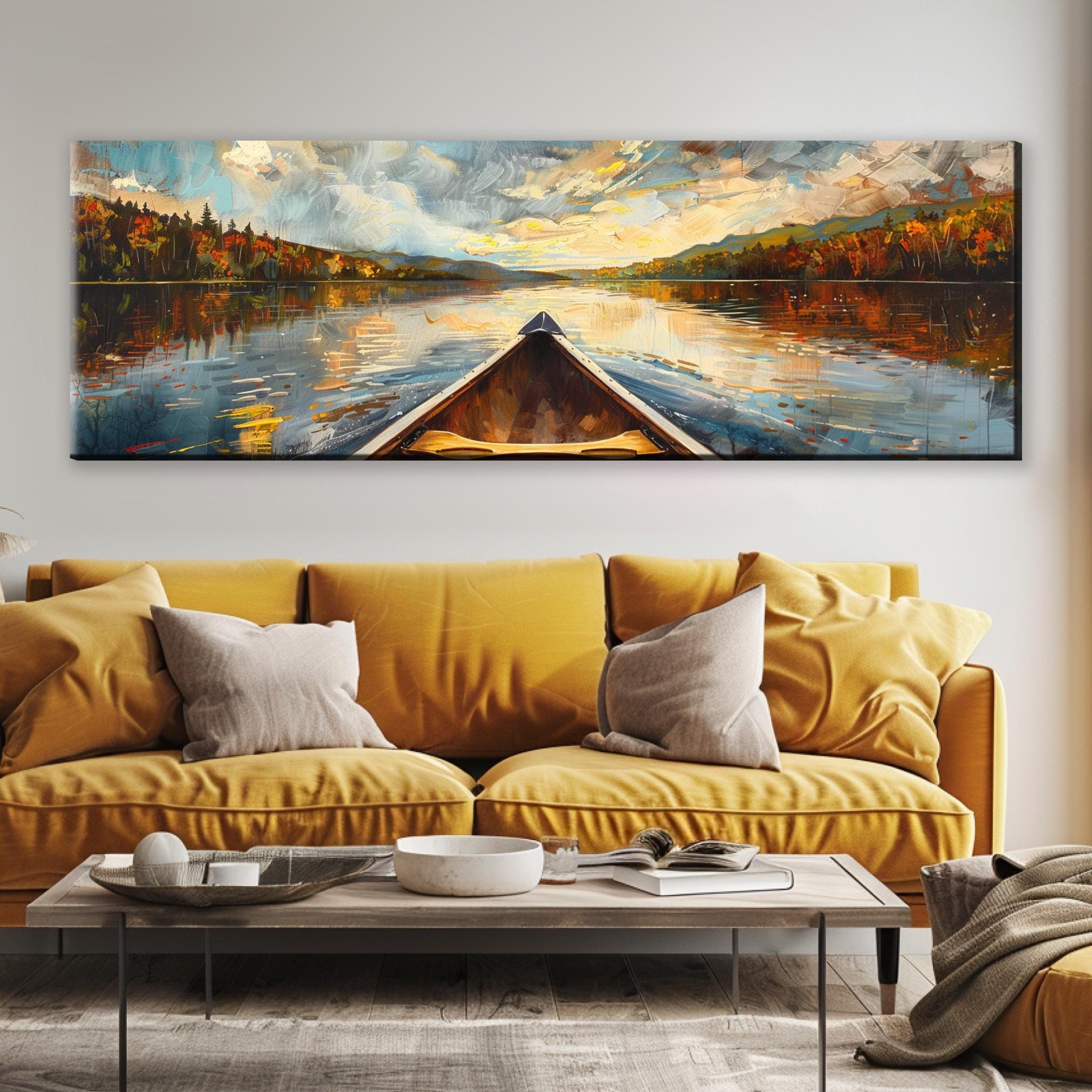 a large painting of a boat on a lake, with a colorful and vibrant landscape in the background. The painting is hung on a wall above a yellow couch, which is positioned in front of a coffee table.