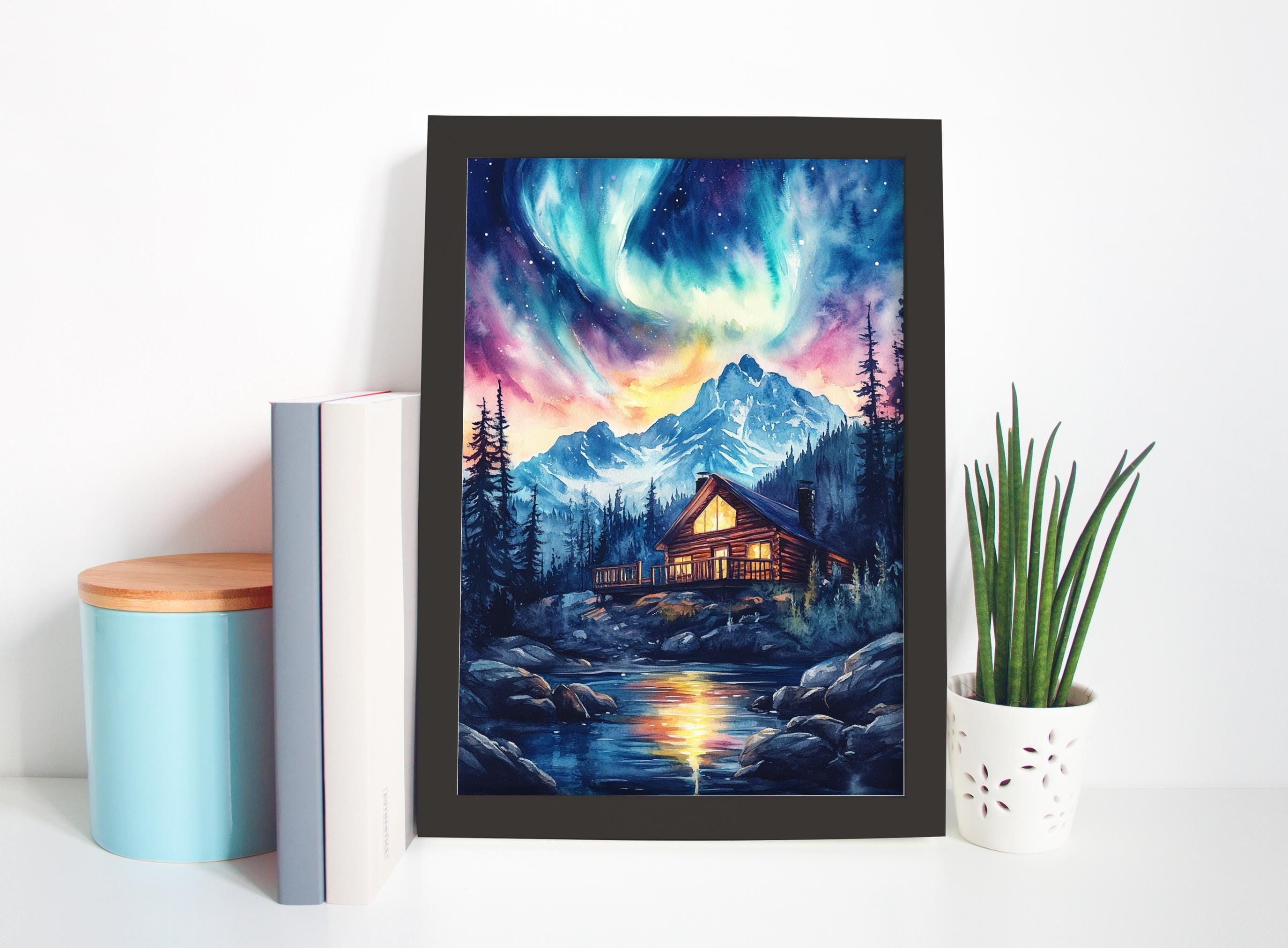 a framed painting depicting a serene mountain landscape with a cabin nestled among the trees, surrounded by a tranquil lake and a stunning display of the northern lights in the night sky.