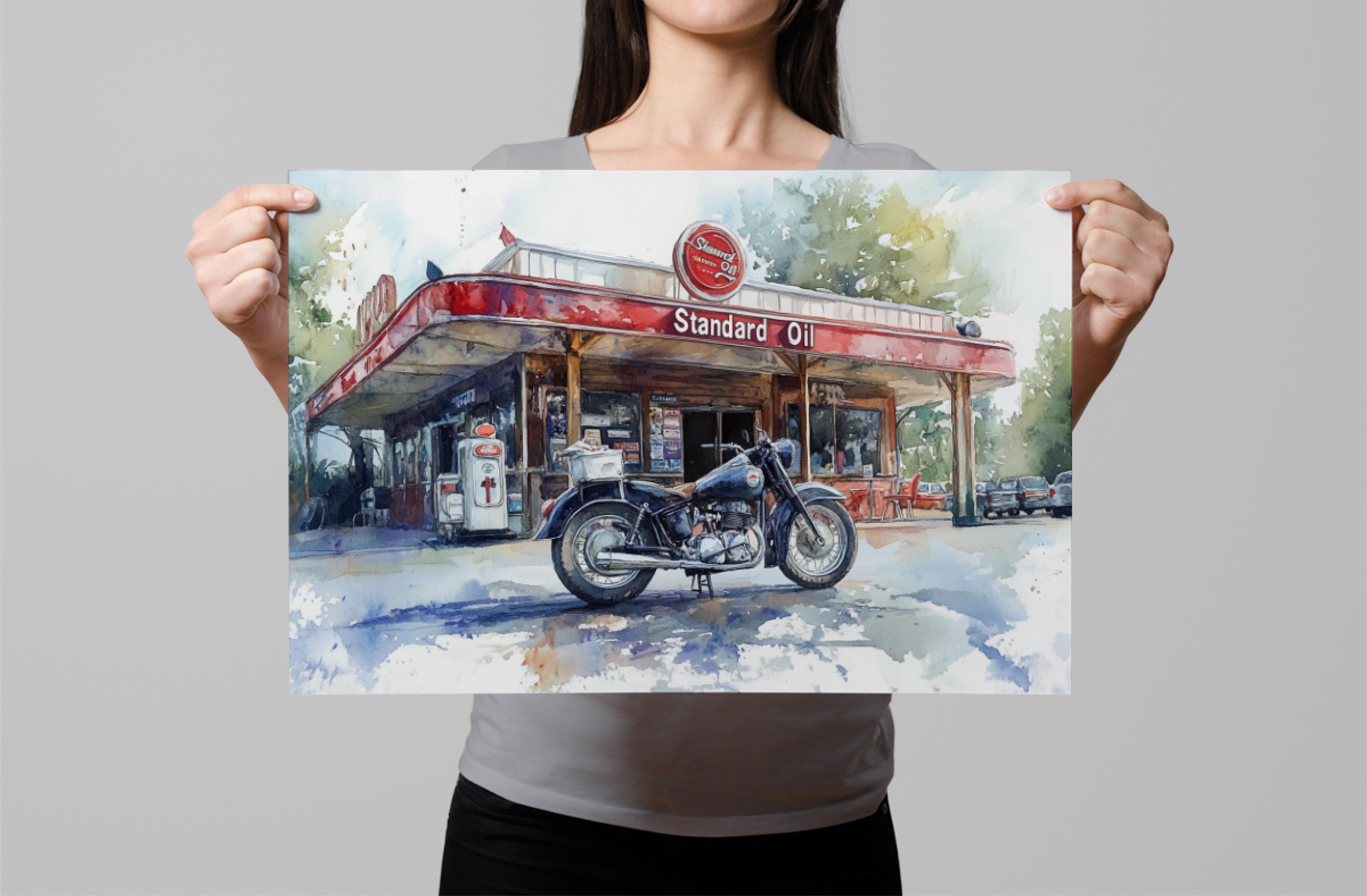 A woman holds up a framed painting depicting a vintage gas station with a motorcycle parked in front.