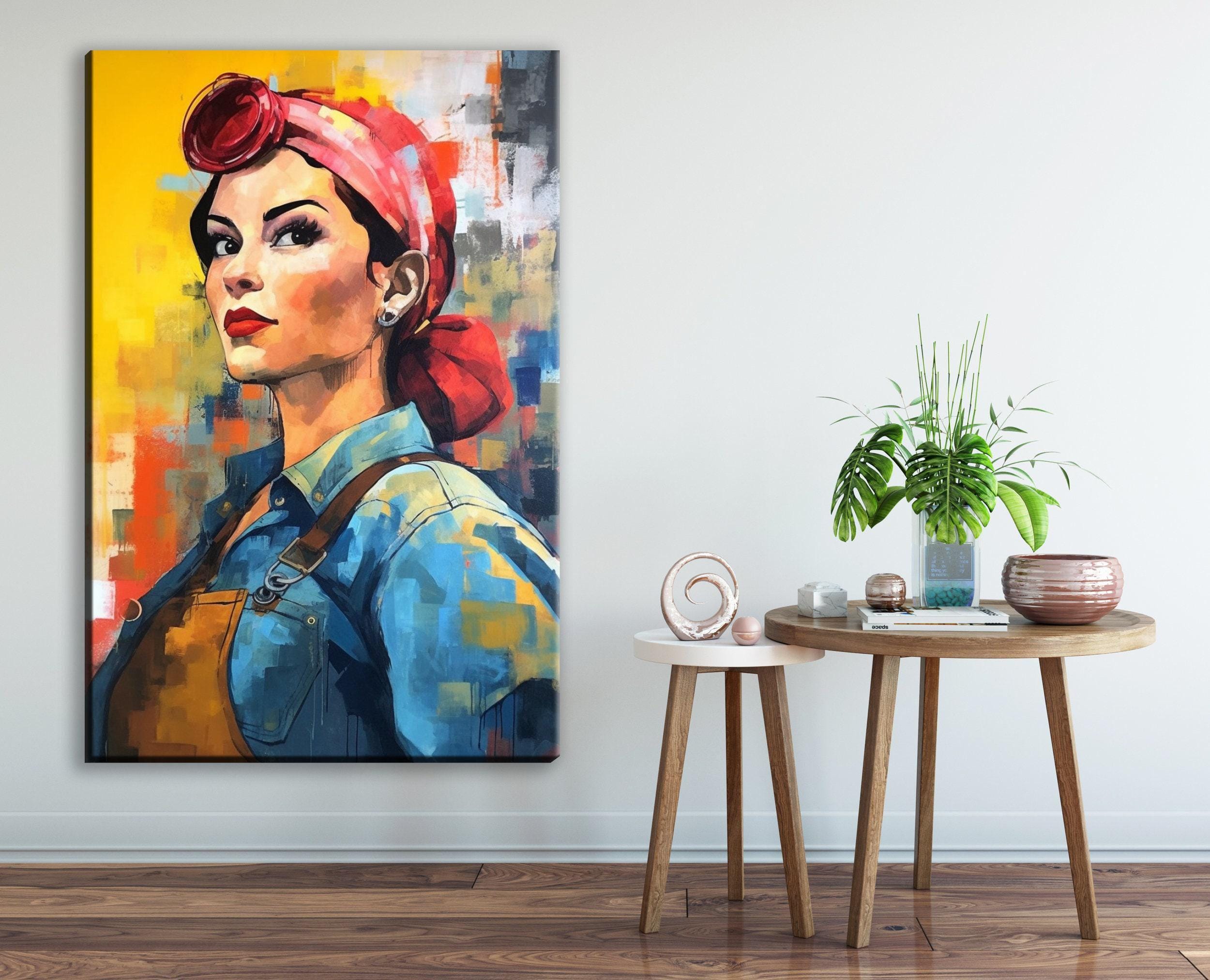a large portrait of a woman with a red headscarf, displayed on a wall next to a small round table with a plant and other decorative items.