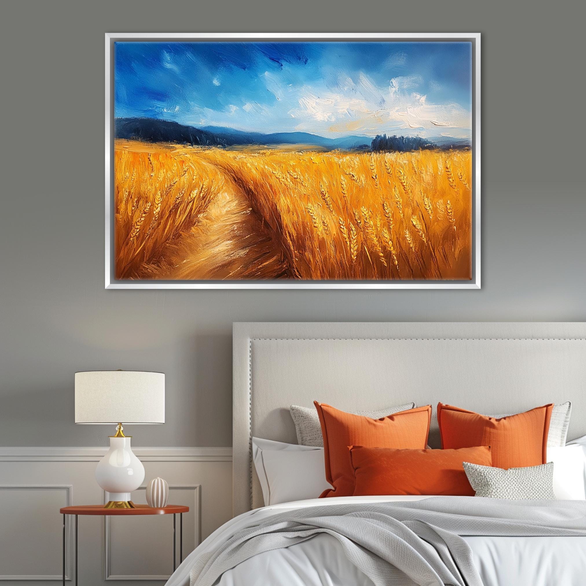 a serene bedroom scene with a large painting of a golden wheat field hanging above a bed with orange pillows.