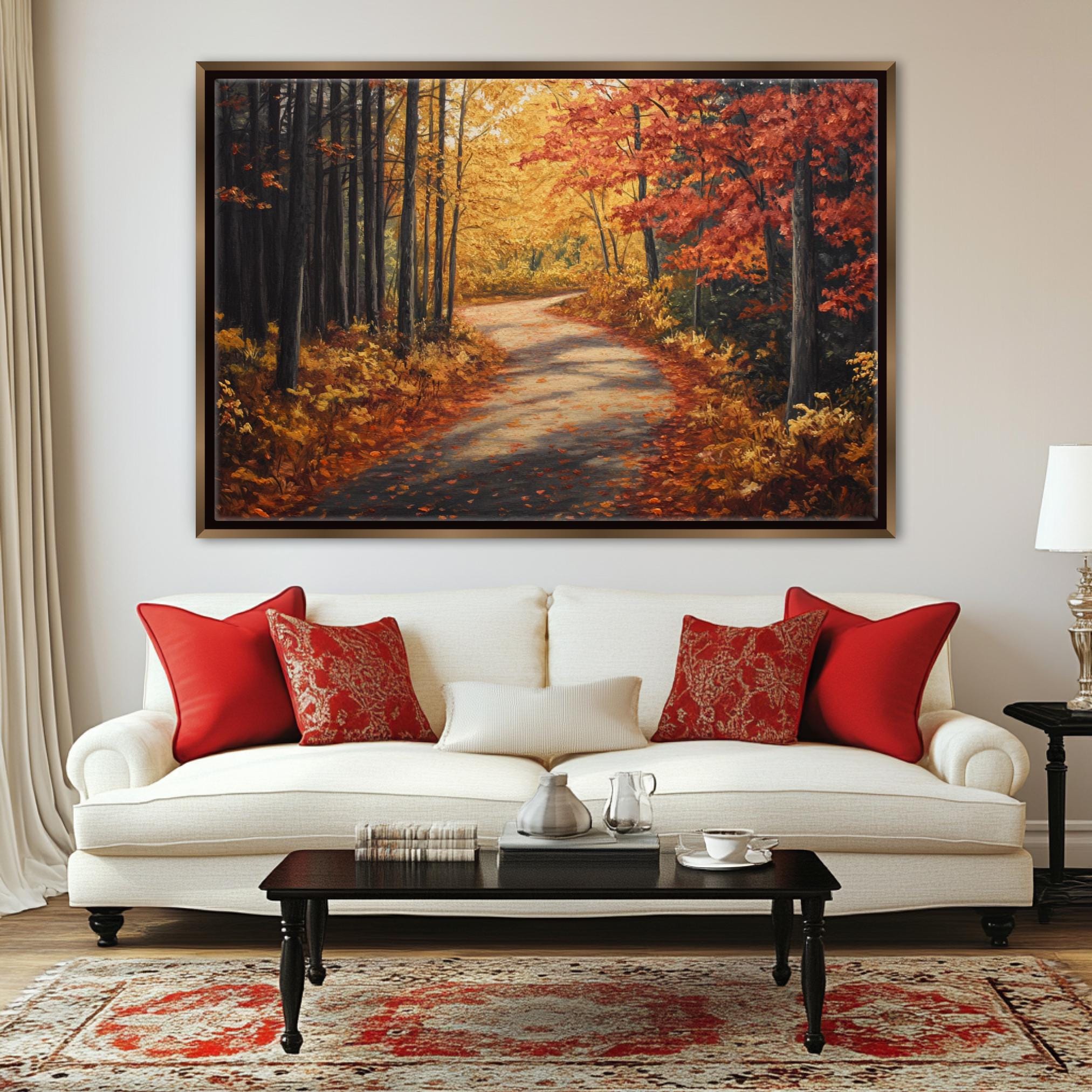 a large painting of a forest path with autumn foliage hanging on a wall above a white sofa with red throw pillows.