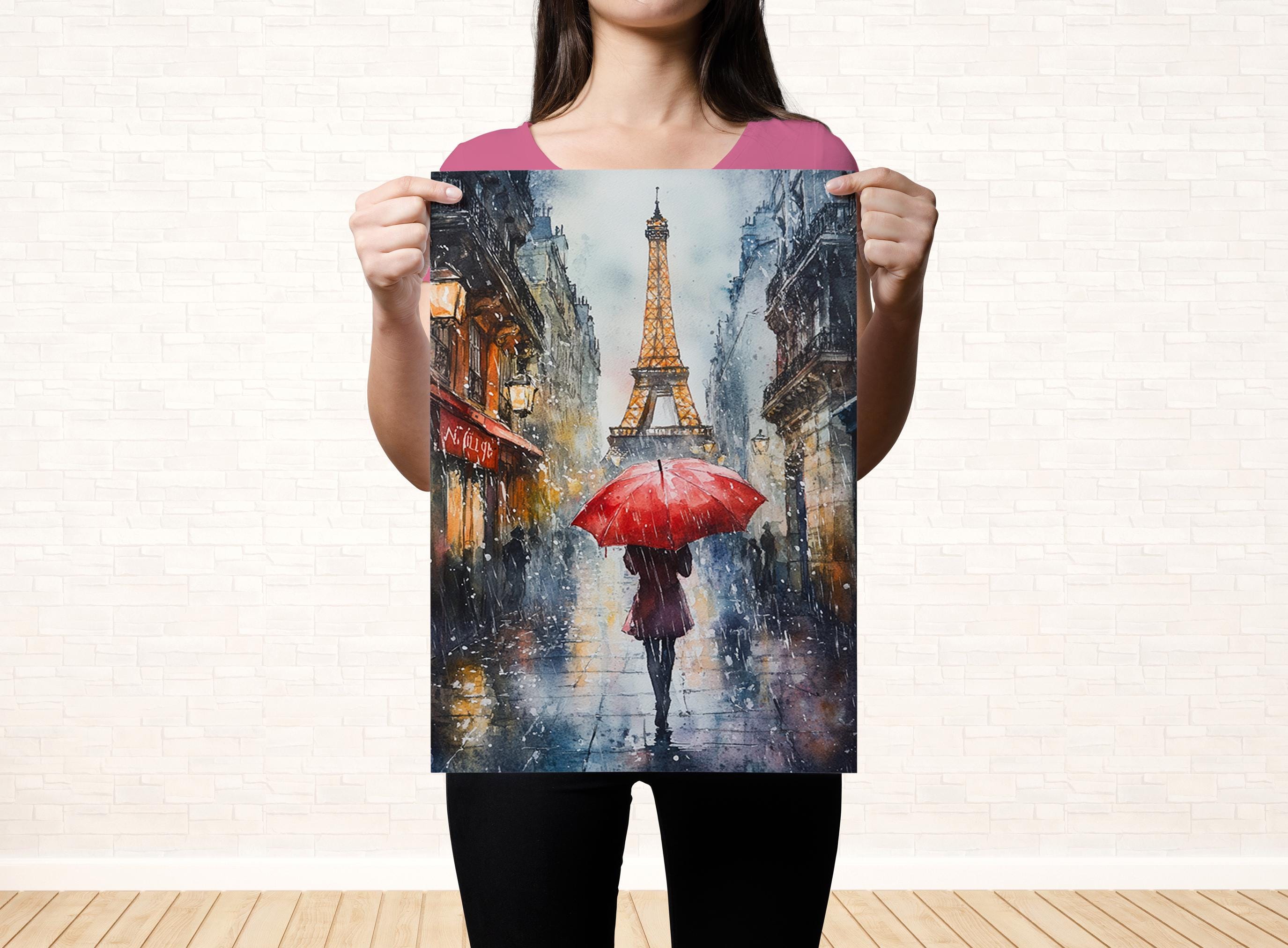 A woman holds up a framed painting depicting a rainy scene with a person walking under an umbrella.