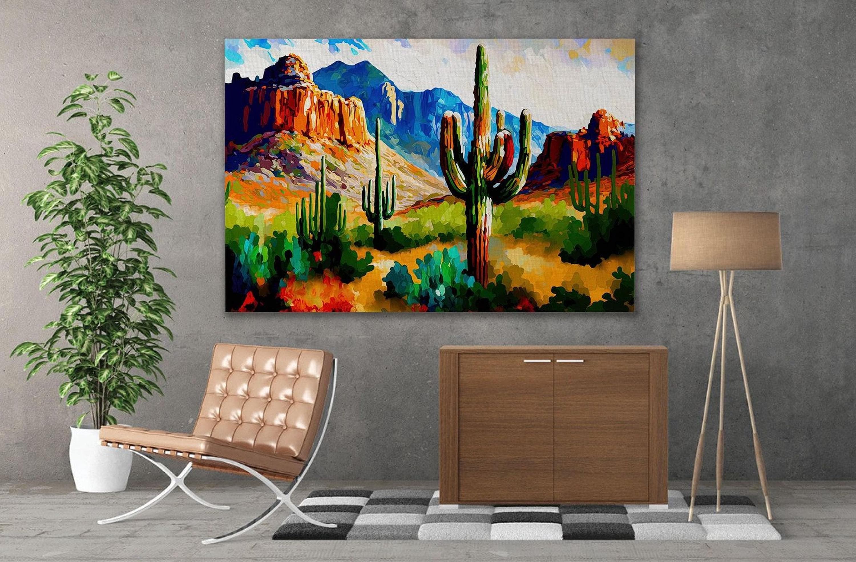 a large painting of a desert landscape with cacti and mountains in the background, hanging on a wall above a brown leather chair and a wooden cabinet.