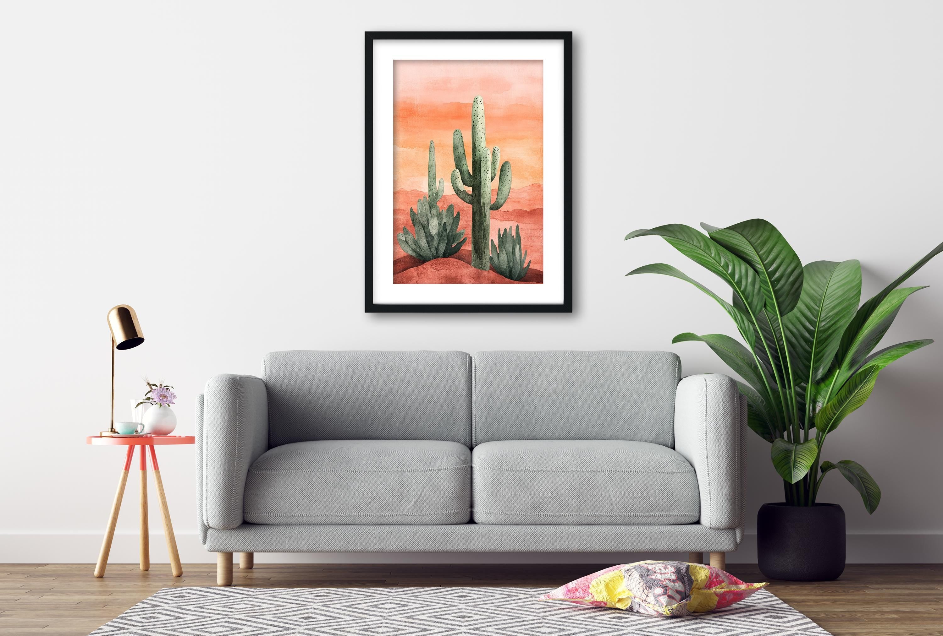 a gray sofa, a framed painting of cacti, a small table with a lamp, and a potted plant, all arranged in a living room setting.