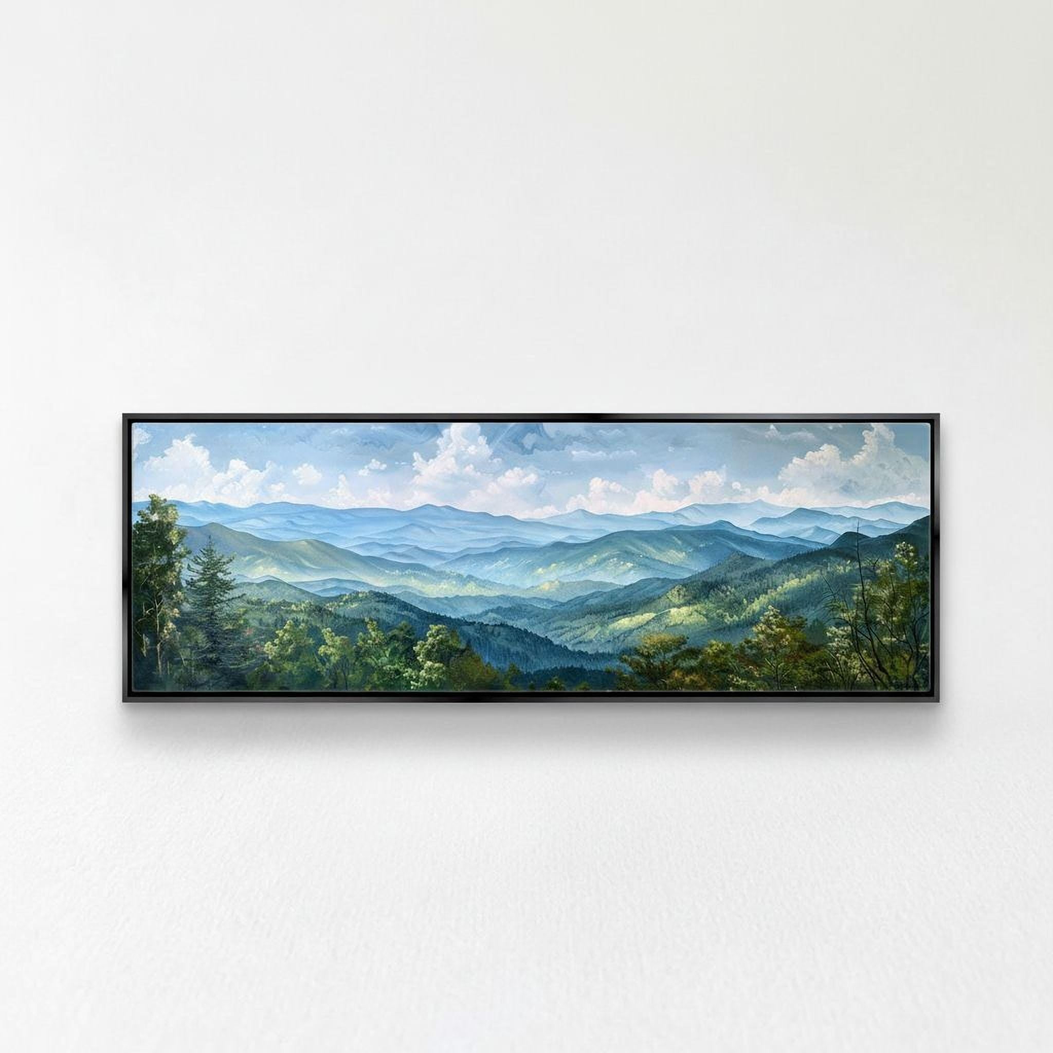 A framed landscape painting depicting a scenic mountain range with rolling hills, lush forests, and a blue sky with fluffy white clouds.