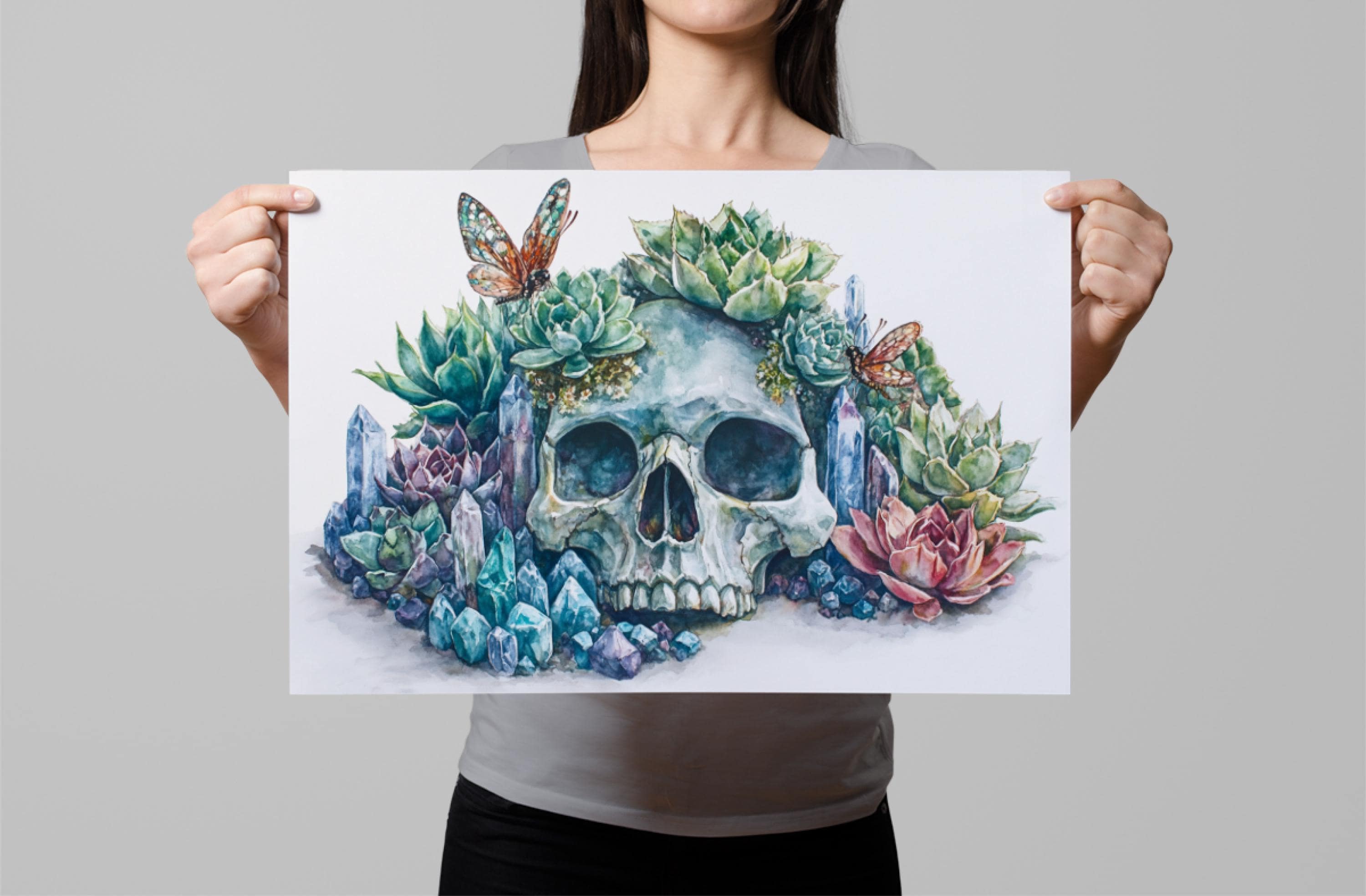 A woman holds up a framed print featuring a surreal, colorful illustration of a skull surrounded by a variety of plants and butterflies.