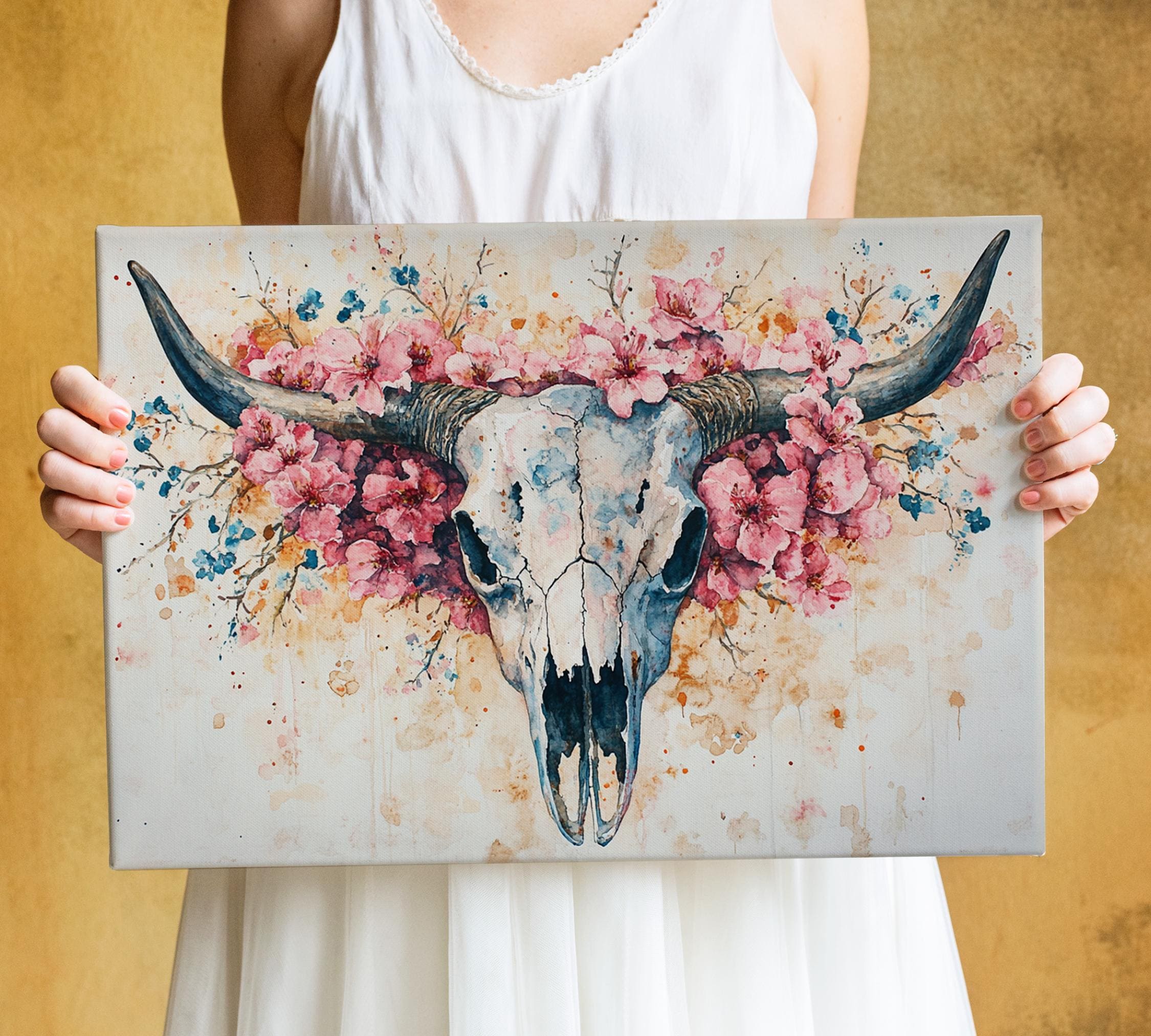A woman holds a framed painting of a skull adorned with pink flowers.