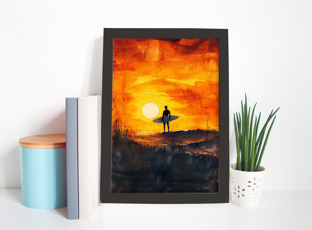 a framed painting depicting a surfer standing on a cliff, silhouetted against a vibrant sunset.