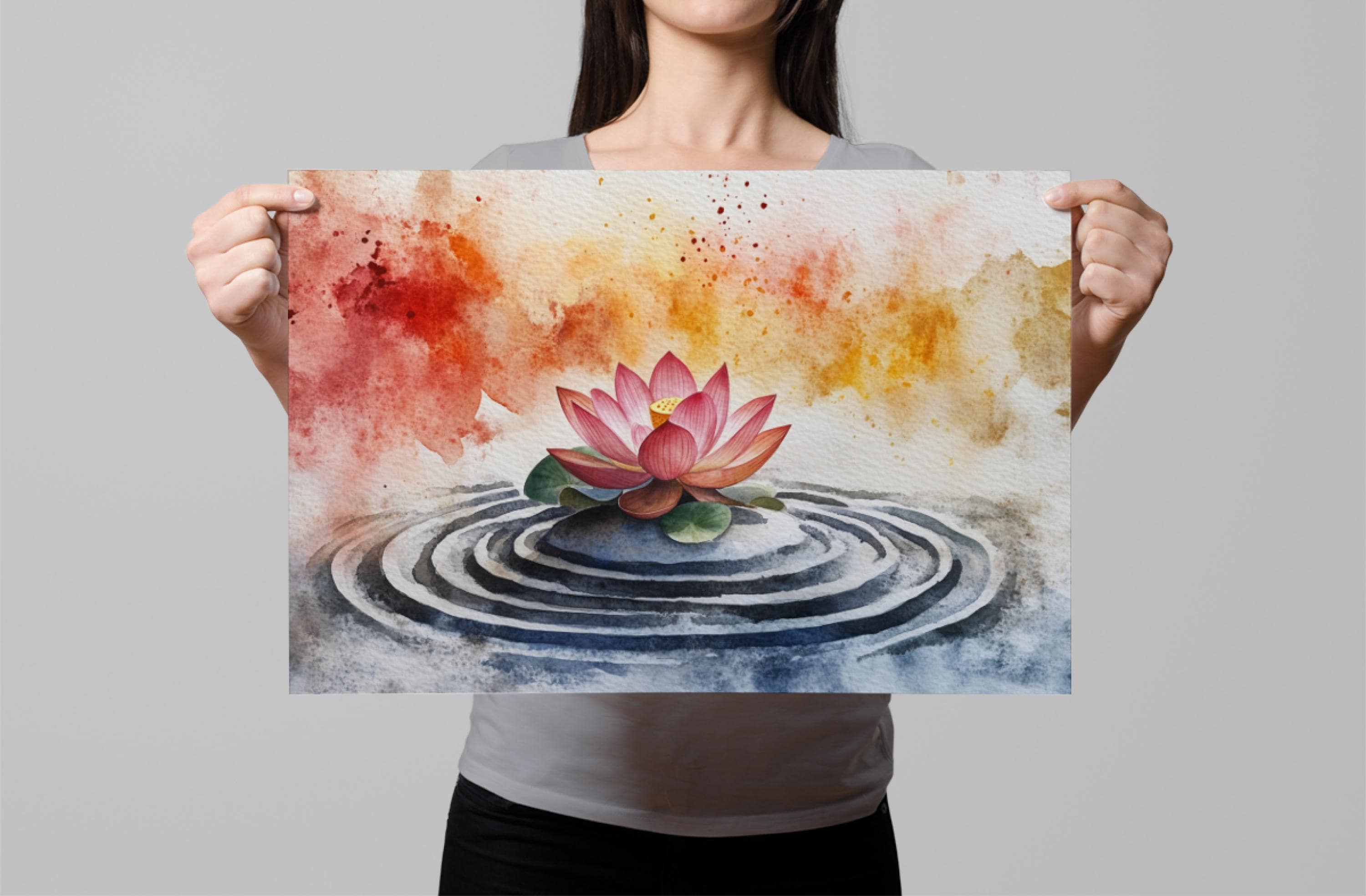 A woman holds up a framed print featuring a watercolor painting of a pink lotus flower in a pond with concentric circles.