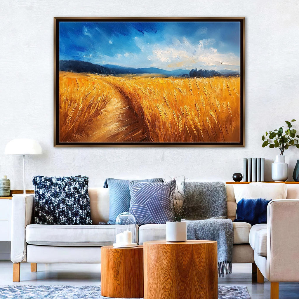 a large painting of a golden wheat field hanging on a wall above a white sofa with various throw pillows.