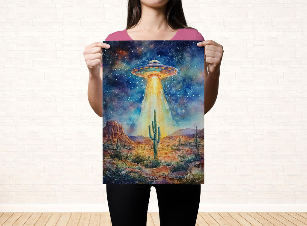 A woman holds up a poster featuring a vibrant, colorful painting of an alien spacecraft hovering over a desert landscape with mountains in the background.