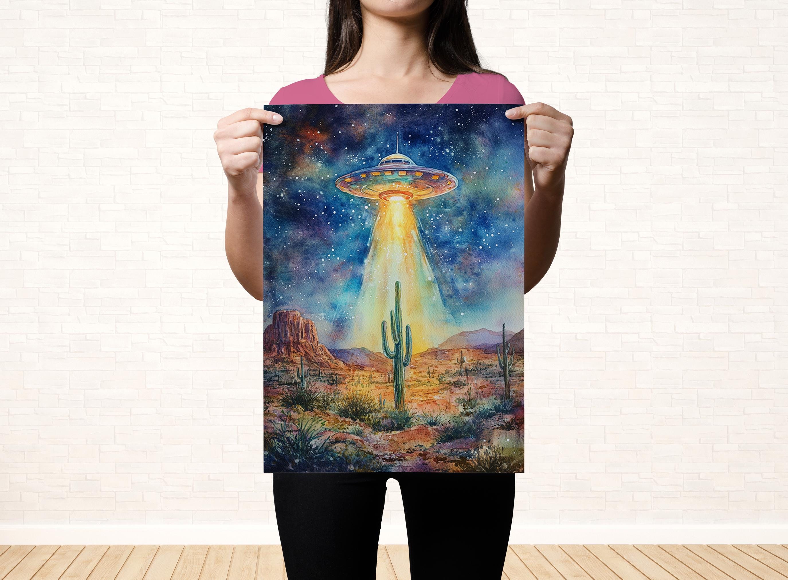 A woman holds up a poster featuring a vibrant, colorful painting of an alien spacecraft hovering over a desert landscape with mountains in the background.