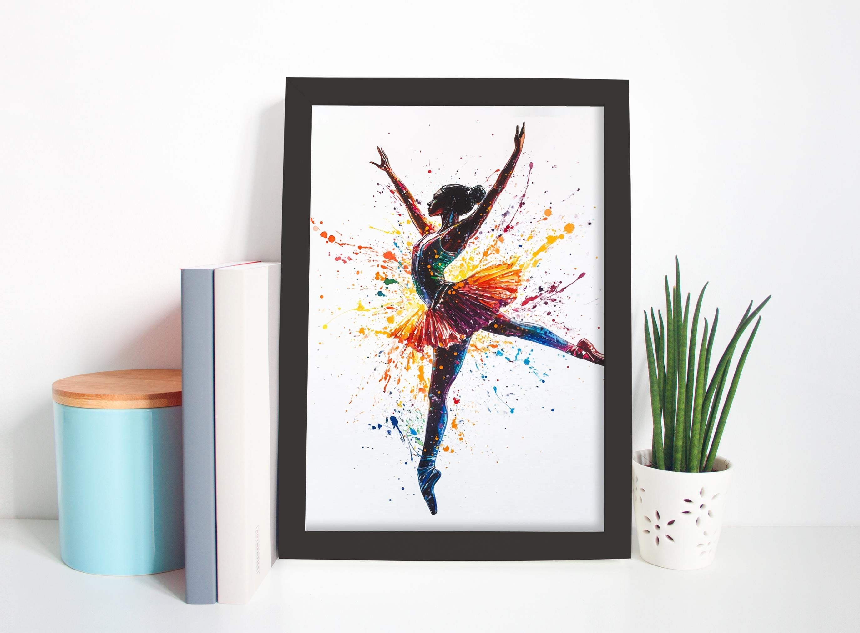 a framed painting of a ballerina in a dynamic pose, surrounded by splashes of color, placed on a shelf next to a potted plant and some books.