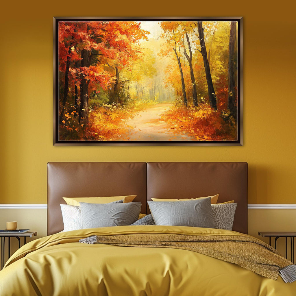 a large framed painting of a forest path with autumn foliage hanging above a bed with a yellow comforter and pillows.
