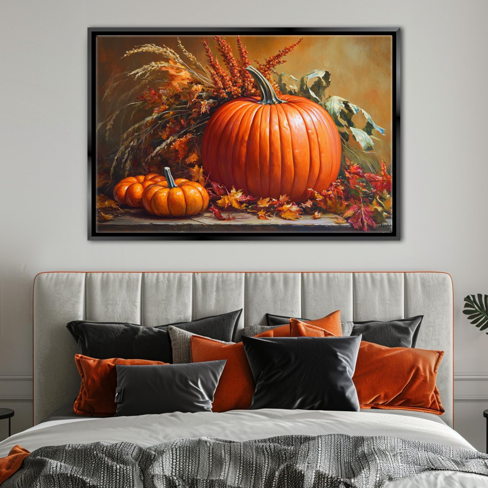 a large framed painting of a pumpkin and autumn foliage hanging above a bed with a gray headboard and black and orange throw pillows.