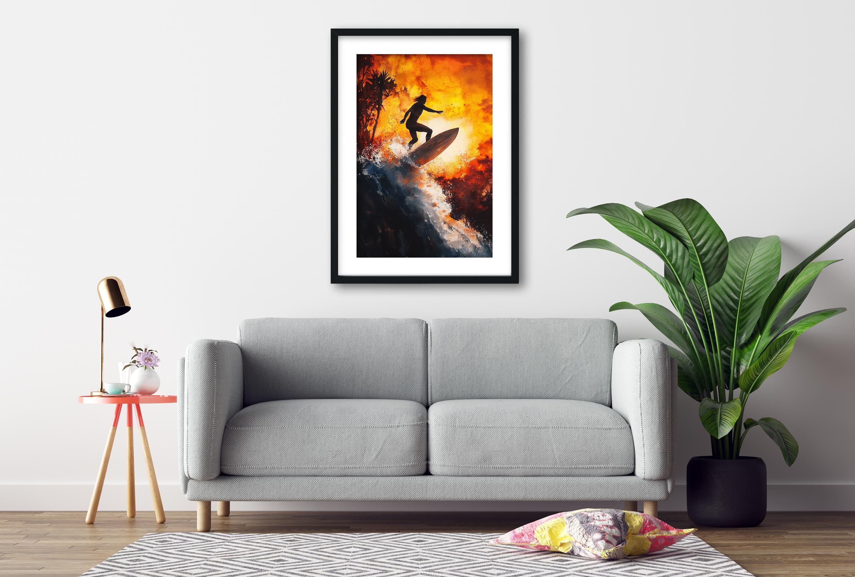 a gray sofa, a framed artwork of a surfer on a wave, a potted plant, and a small table with a lamp.