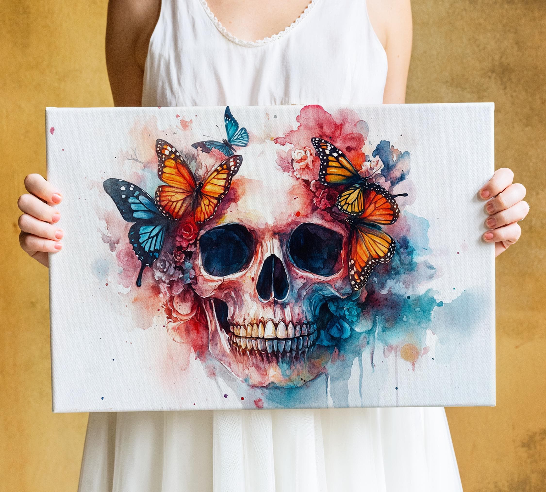 A person is holding a canvas with a colorful and intricate painting of a skull surrounded by butterflies and flowers.