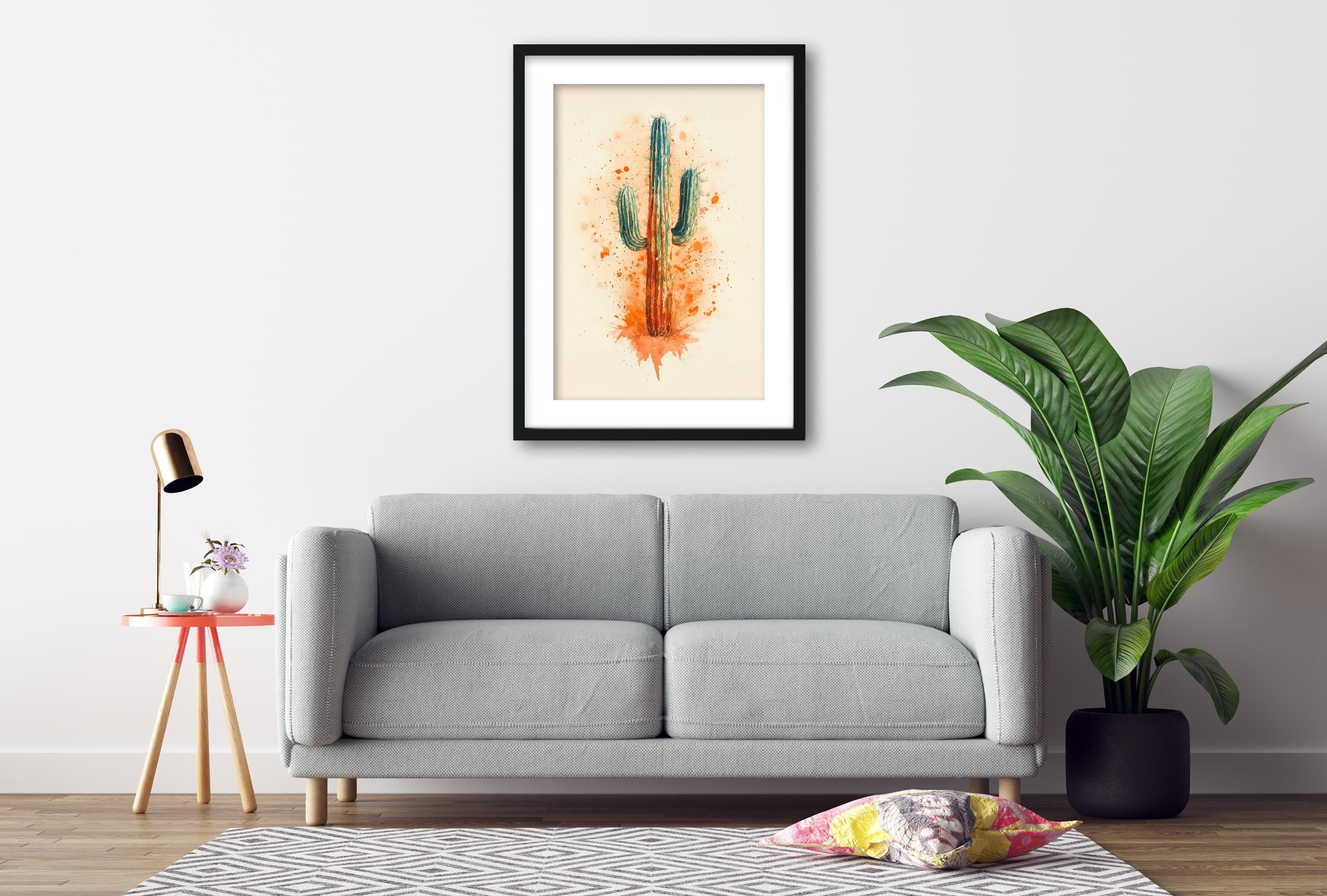 a gray sofa, a framed picture of a cactus, a small table with a lamp, and a potted plant, all arranged in a living room setting.