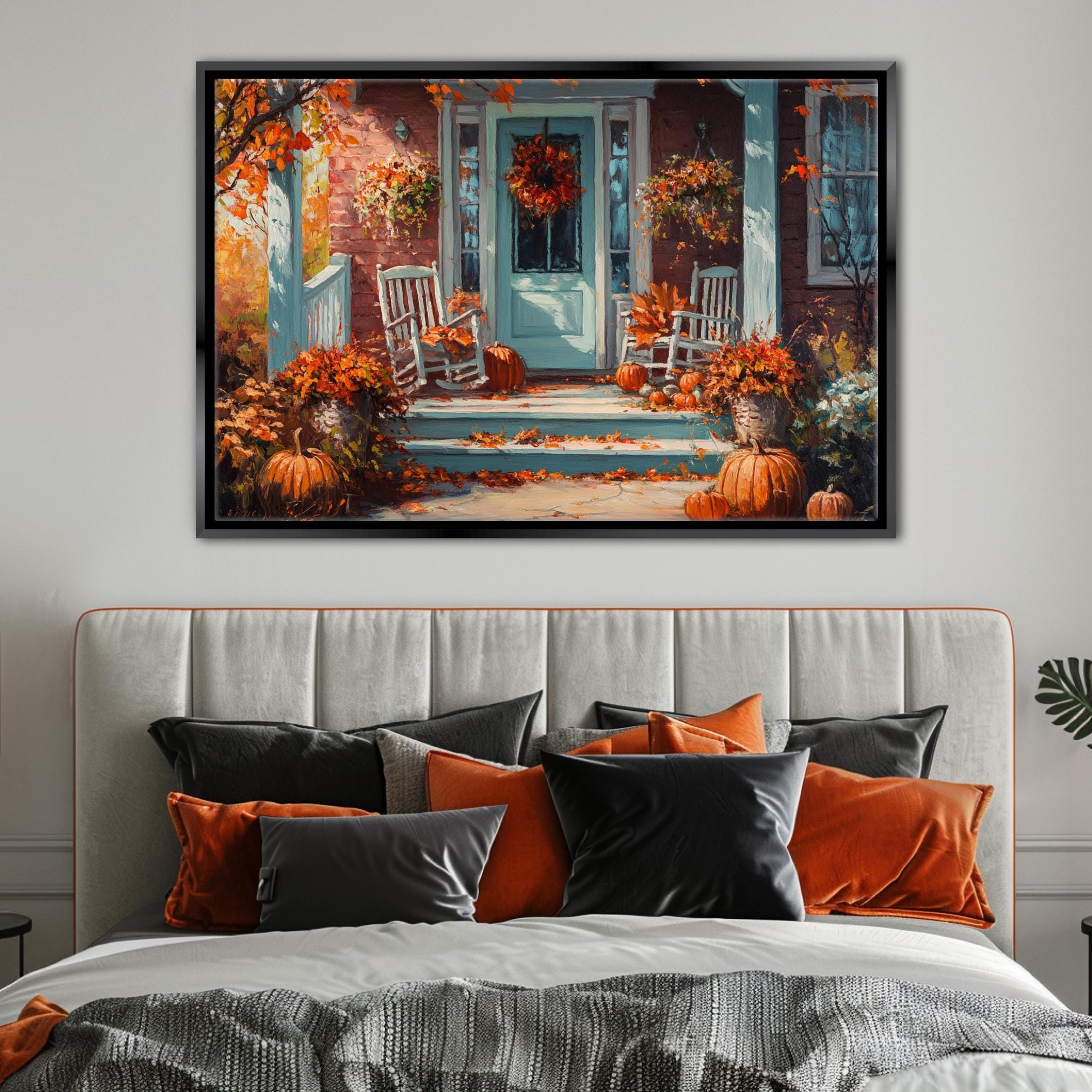 a cozy autumn scene with a white house, a porch, and a wreath on the door. The porch is decorated with pumpkins and other fall foliage, creating a warm and inviting atmosphere. The painting is hung on a wall above a bed with a gray headboard and a gray comforter.