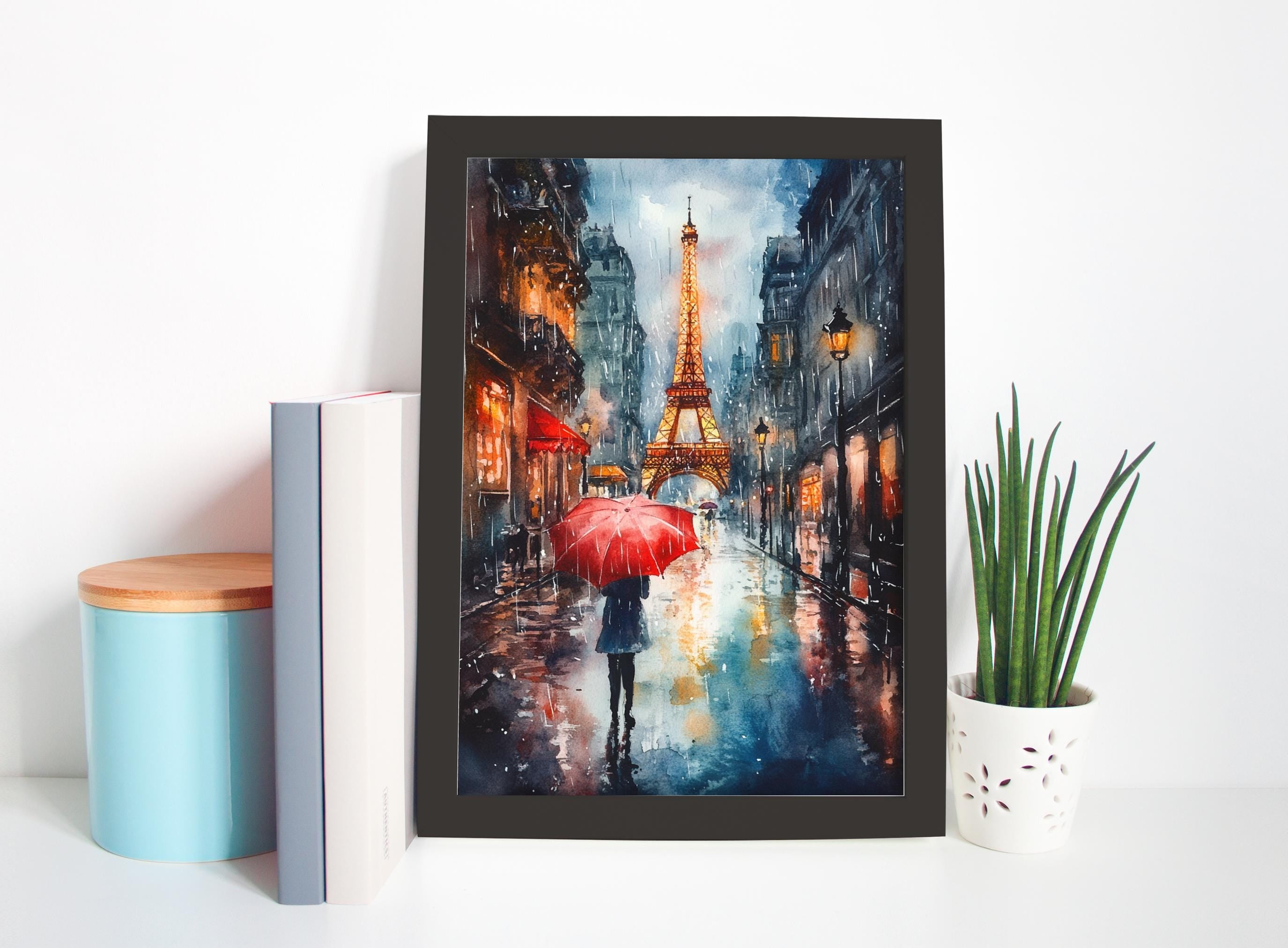 a framed painting of a rainy street scene with a person holding a red umbrella, with the Eiffel Tower visible in the background.
