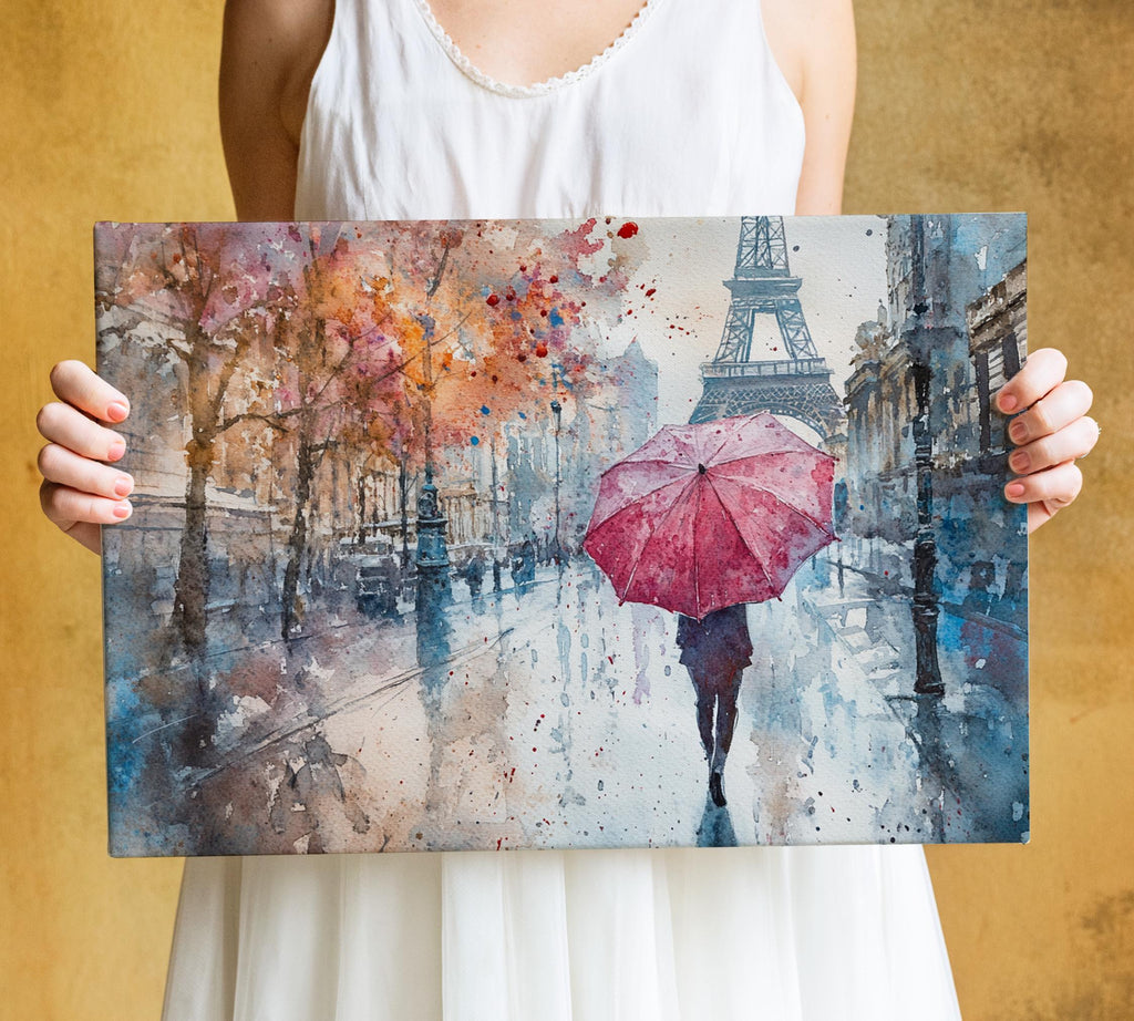 A woman holds a watercolor painting depicting a rainy street scene with a person walking under a red umbrella.