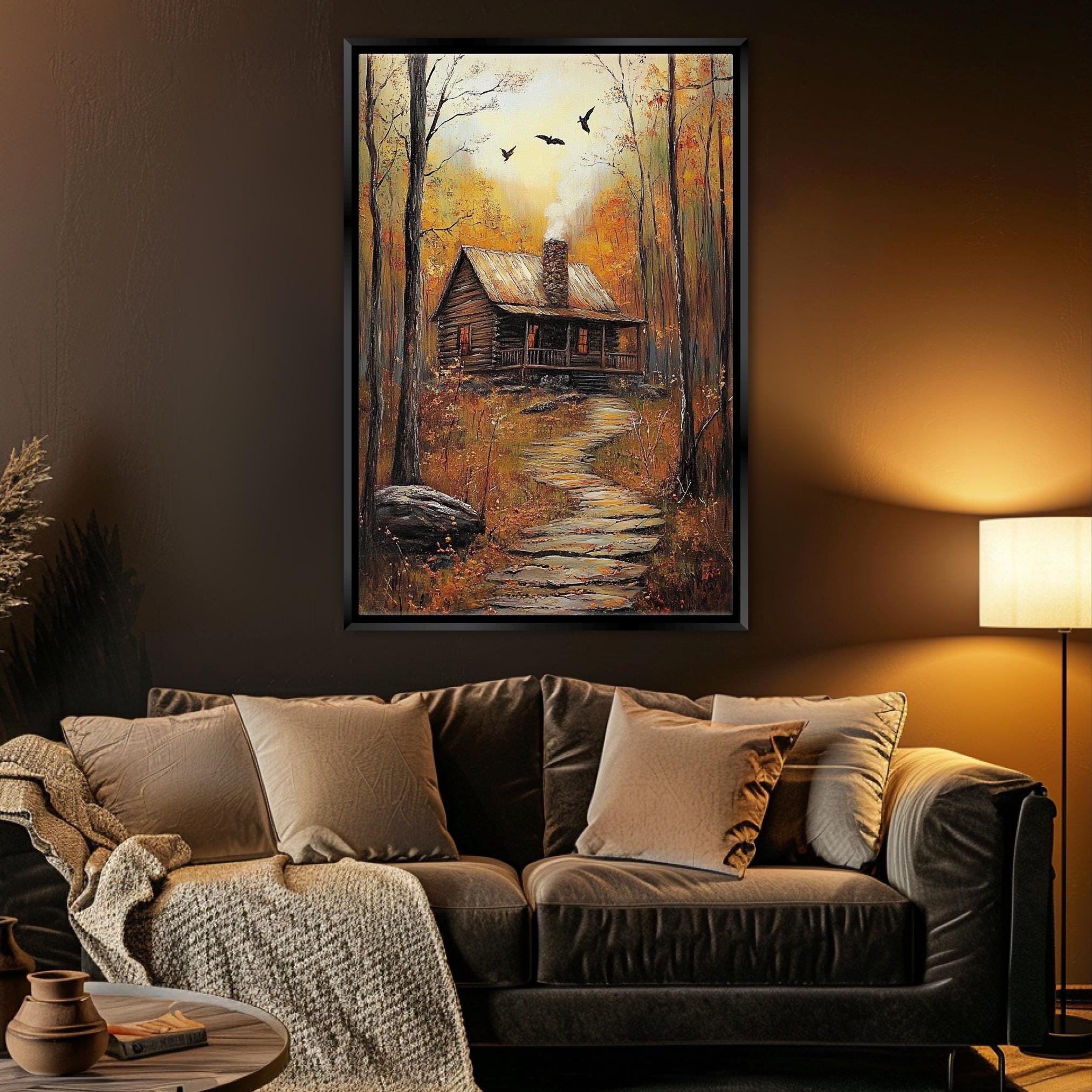 a cozy living room with a large painting of a cabin in the woods hanging on the wall above a brown leather couch.