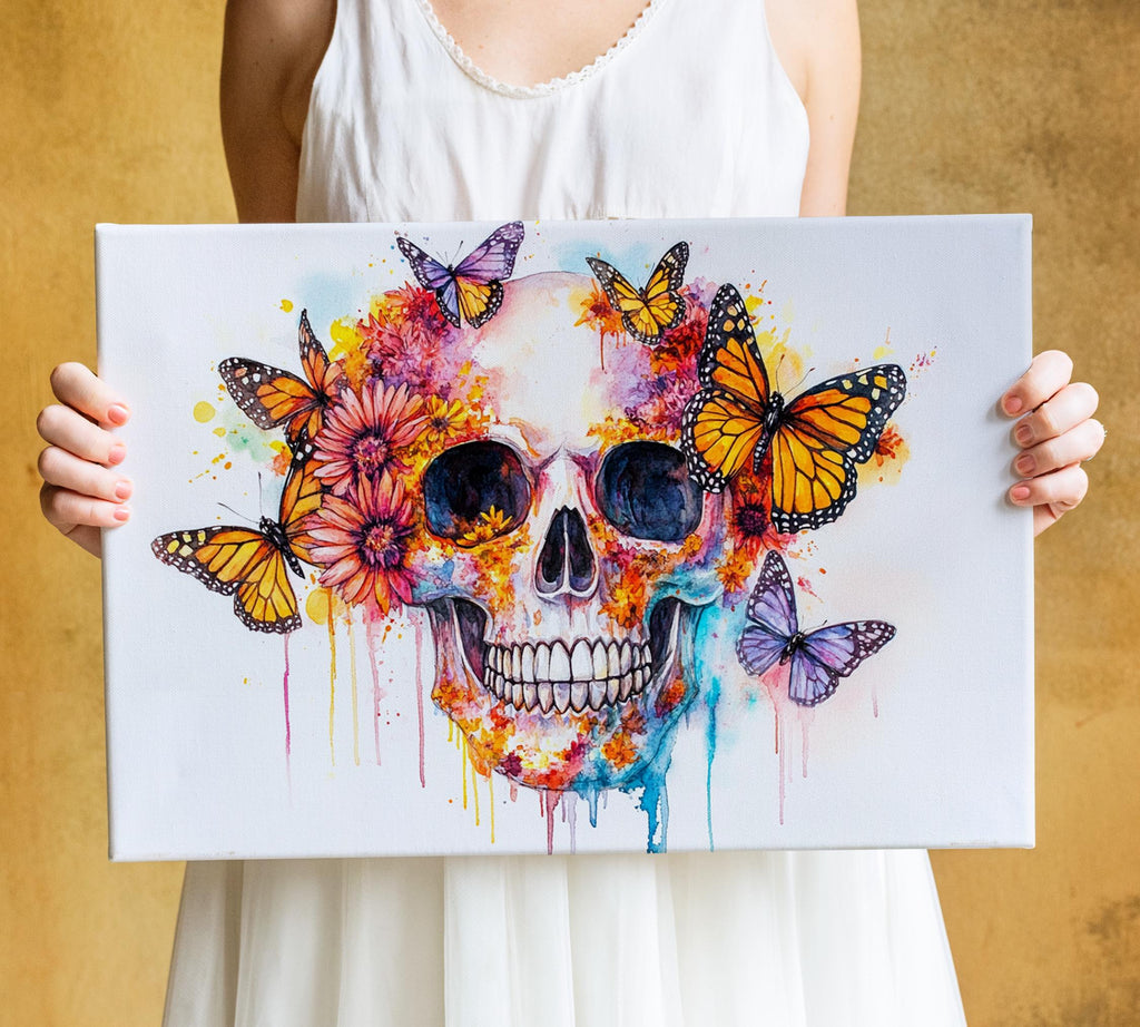 A person is holding a canvas with a colorful and artistic depiction of a skull surrounded by butterflies and flowers.