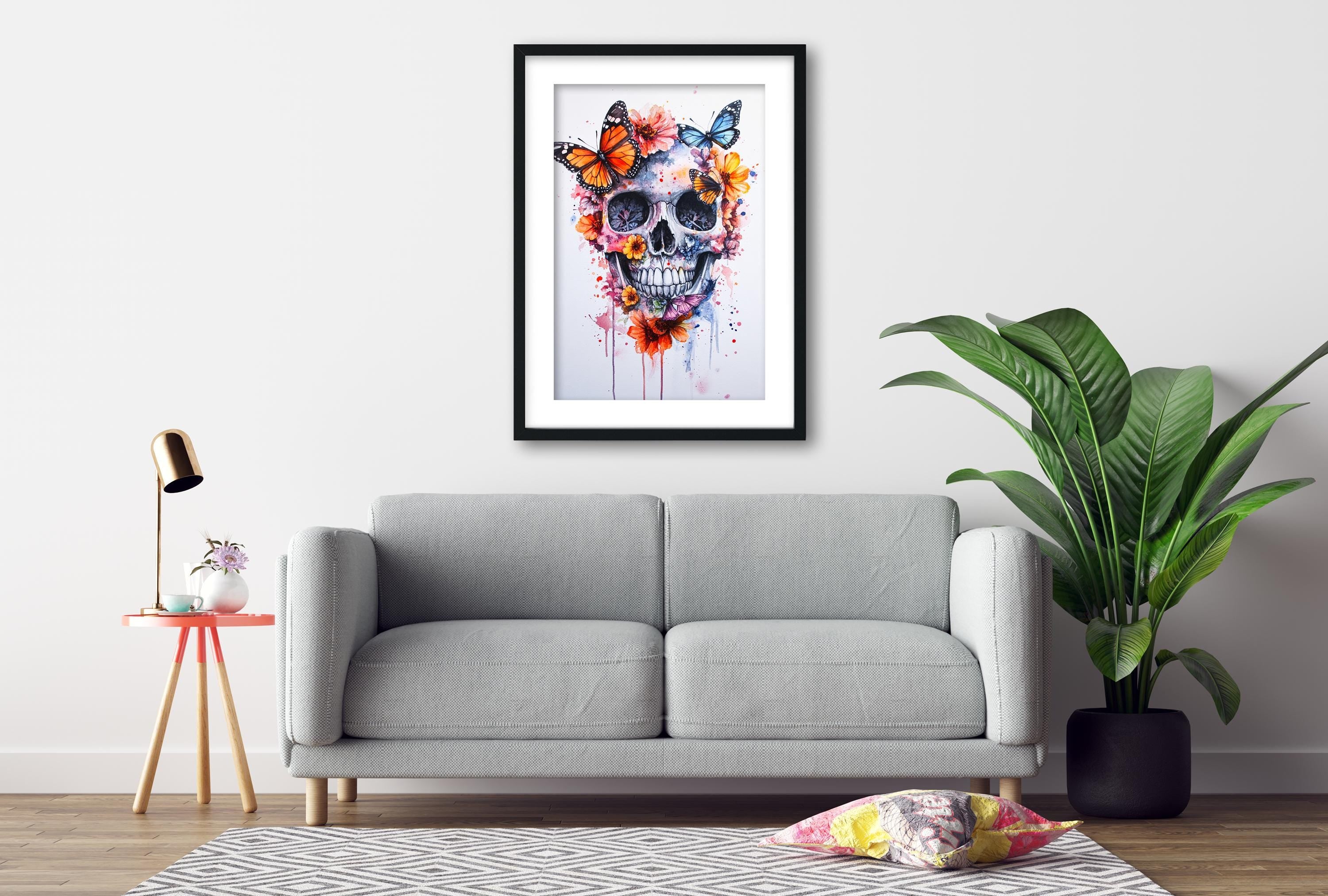 a gray sofa, a framed artwork of a skull with butterflies, a small table with a lamp, and a potted plant, all arranged in a living room setting.