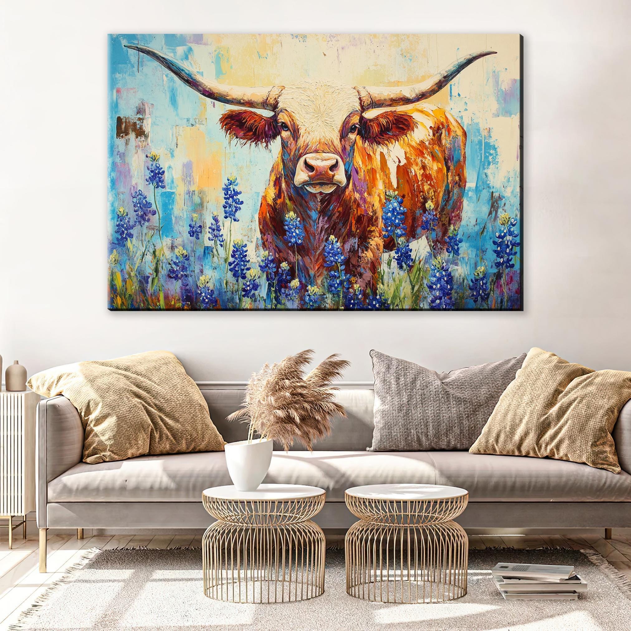 a large painting of a bull with horns, surrounded by a field of blue flowers, hanging on a wall above a gray couch with decorative pillows.